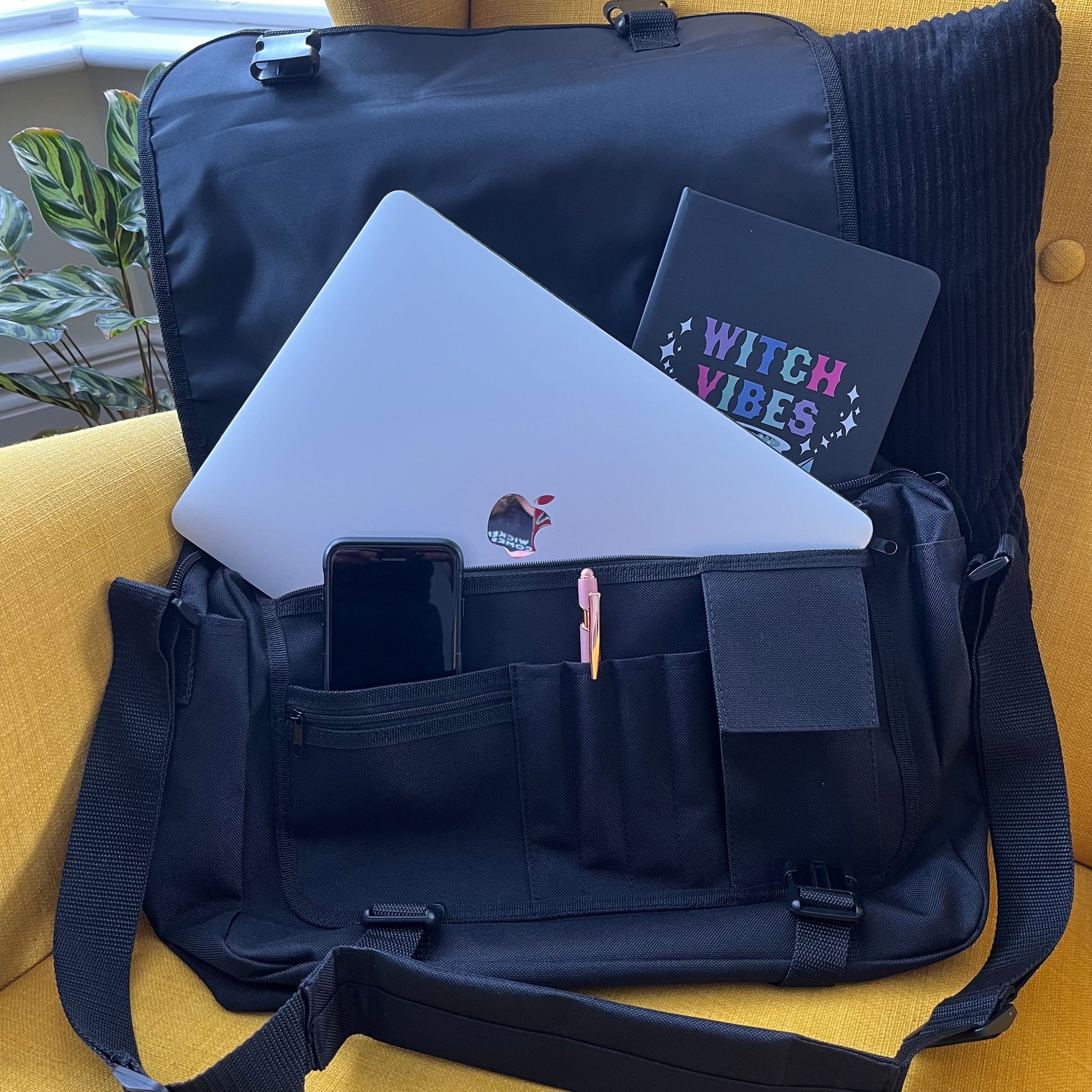 Black backpack with laptop, phone, and notebook on a yellow surface