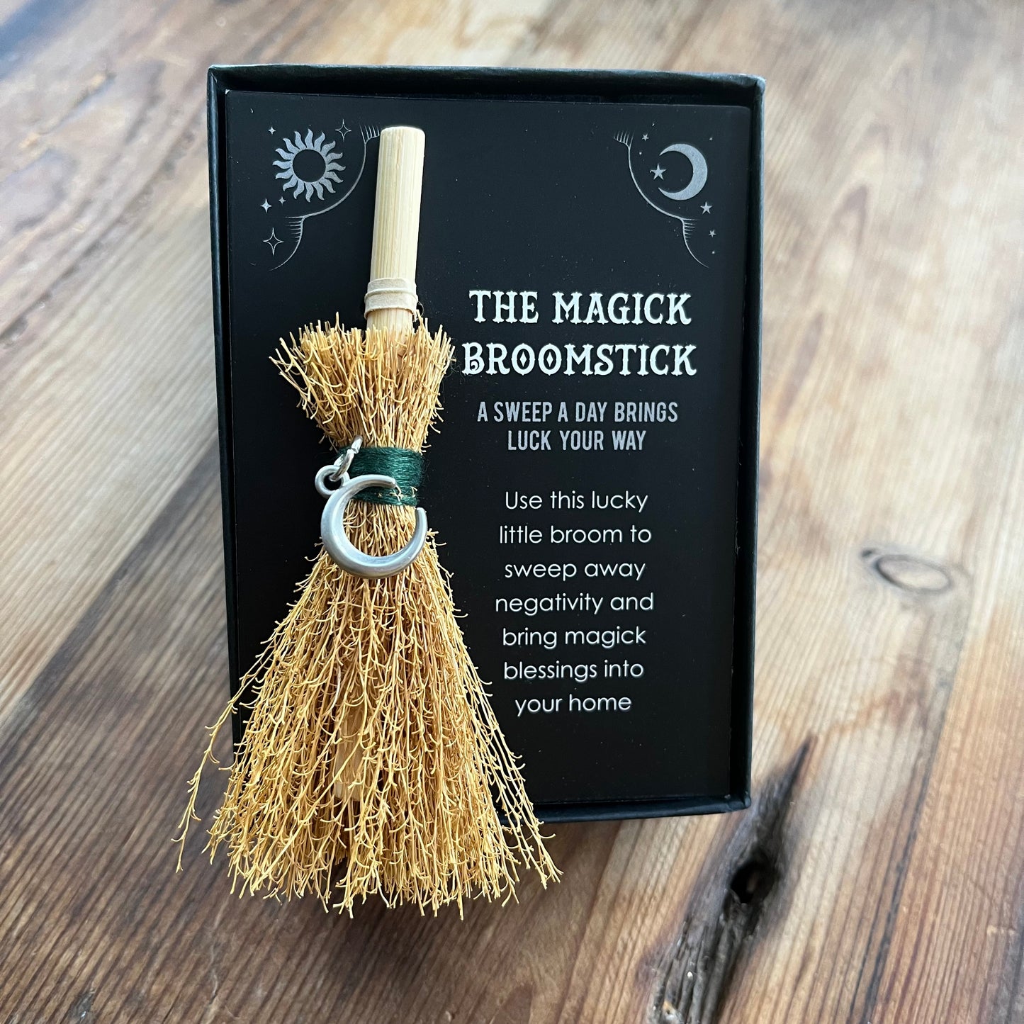 Magick broomstick with packaging on a wooden surface