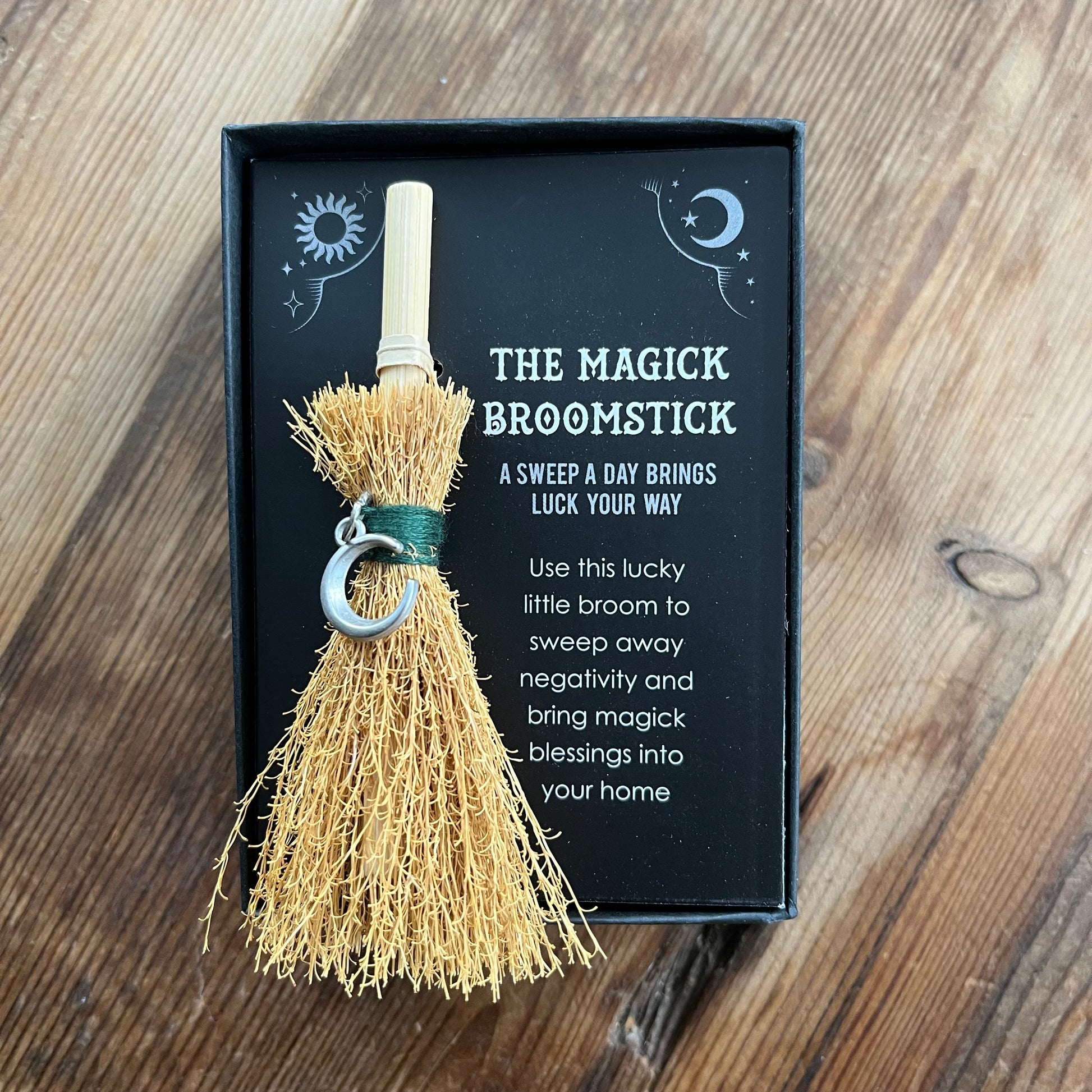 Magick broomstick with packaging on a wooden surface