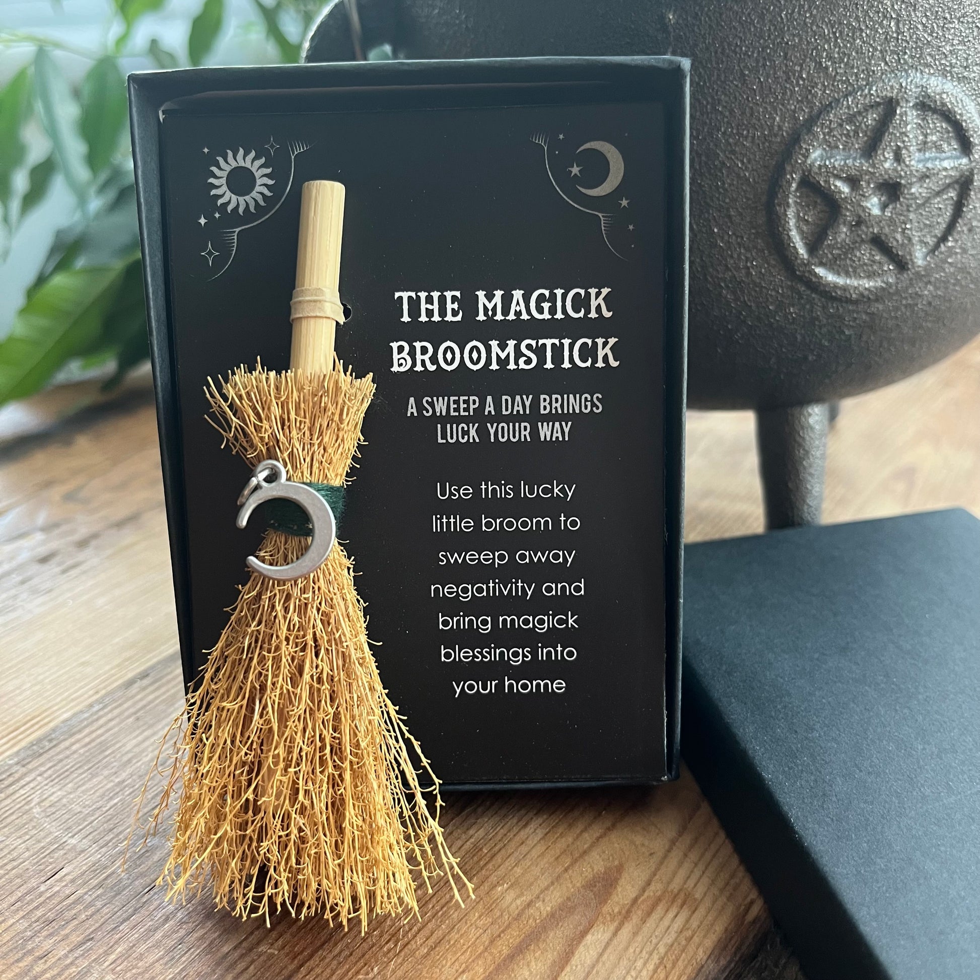 Magick broomstick with packaging on a wooden surface