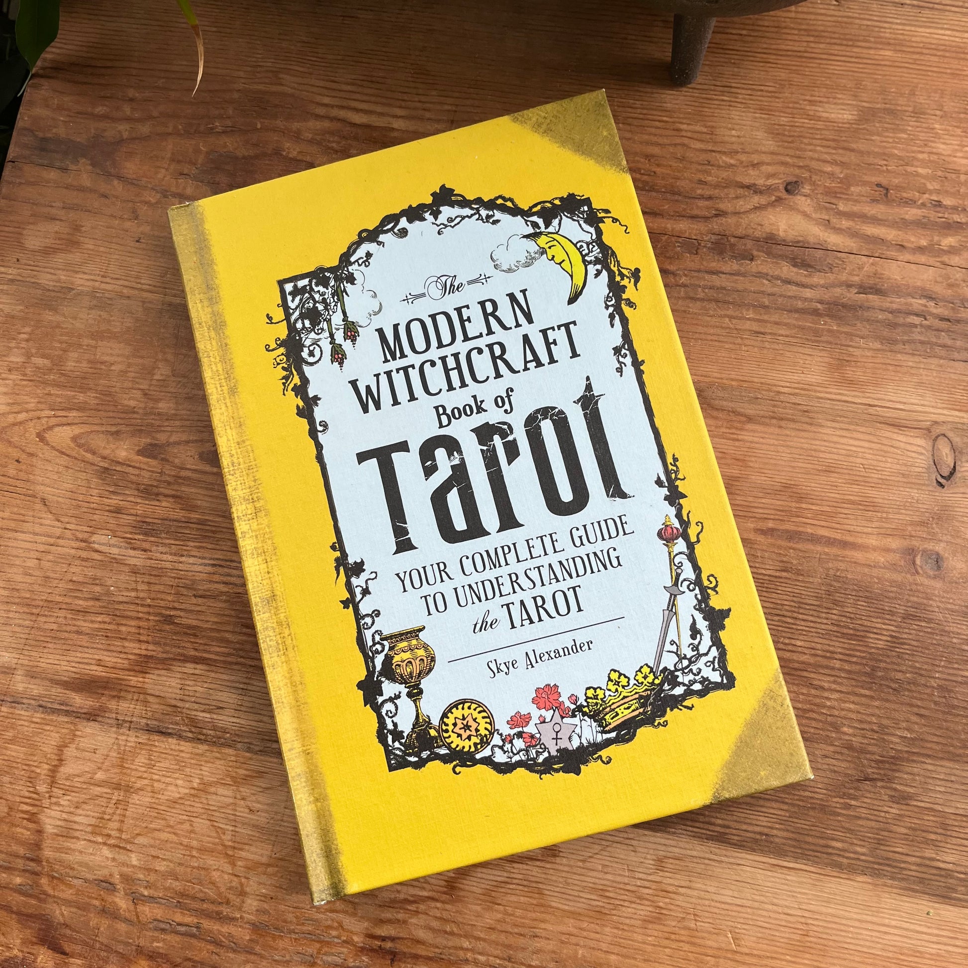 Book titled 'Modern Witchcraft Book of Tarot' on a wooden surface