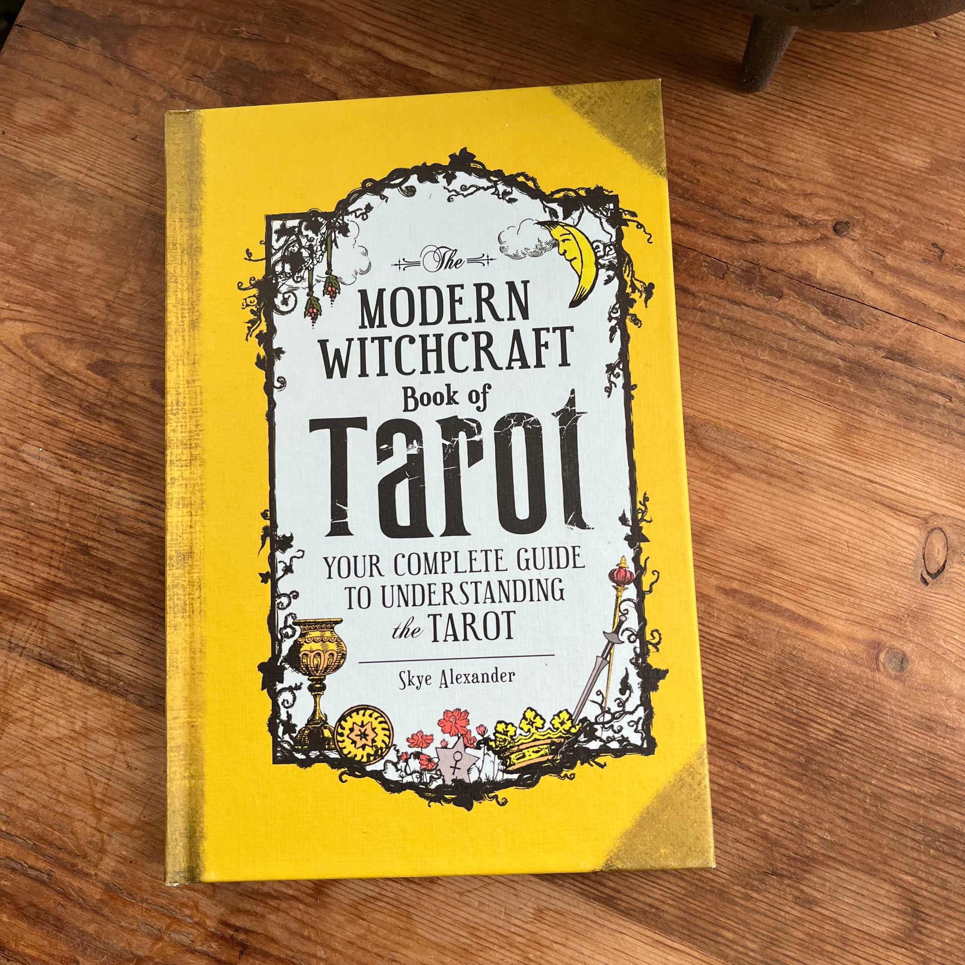 Book titled 'Modern Witchcraft Book of Tarot' on a wooden surface