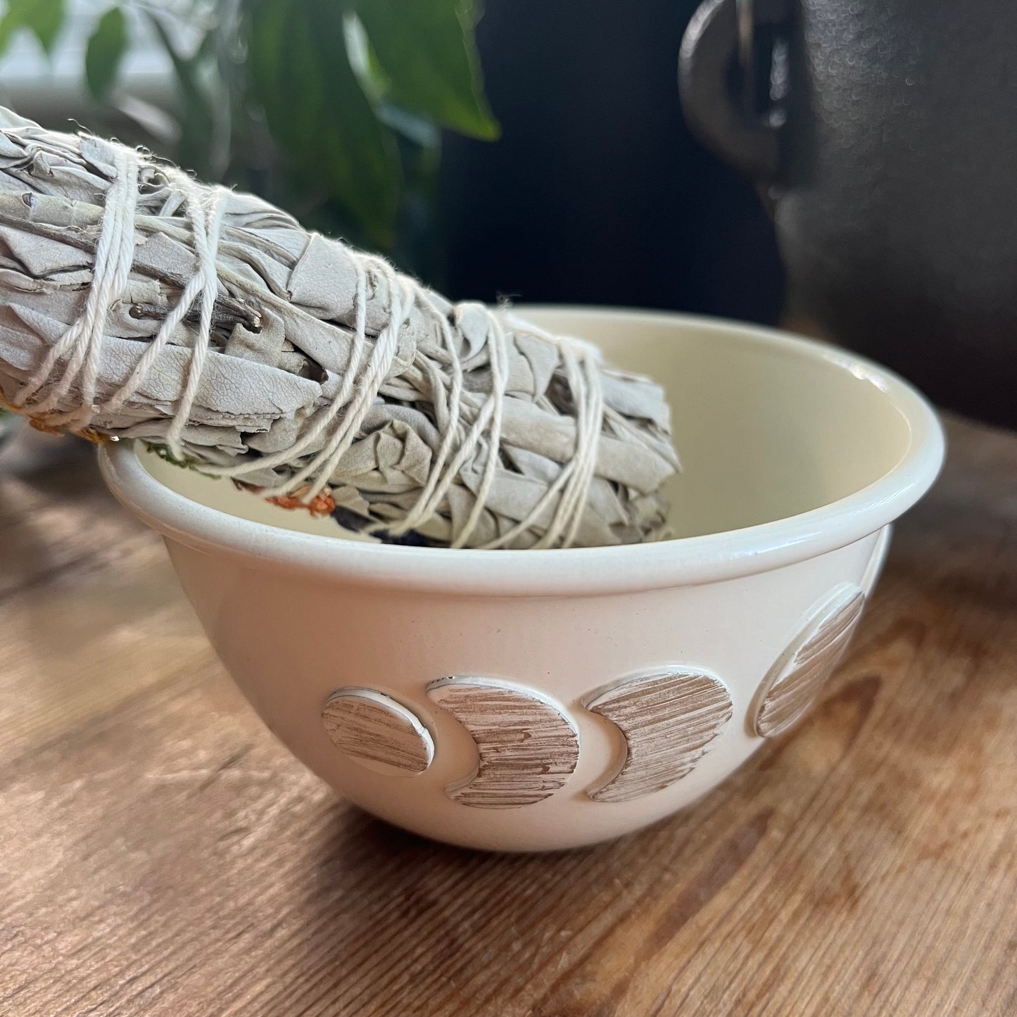 White moon phase decorative ceramic smudge bowl on a wooden surface