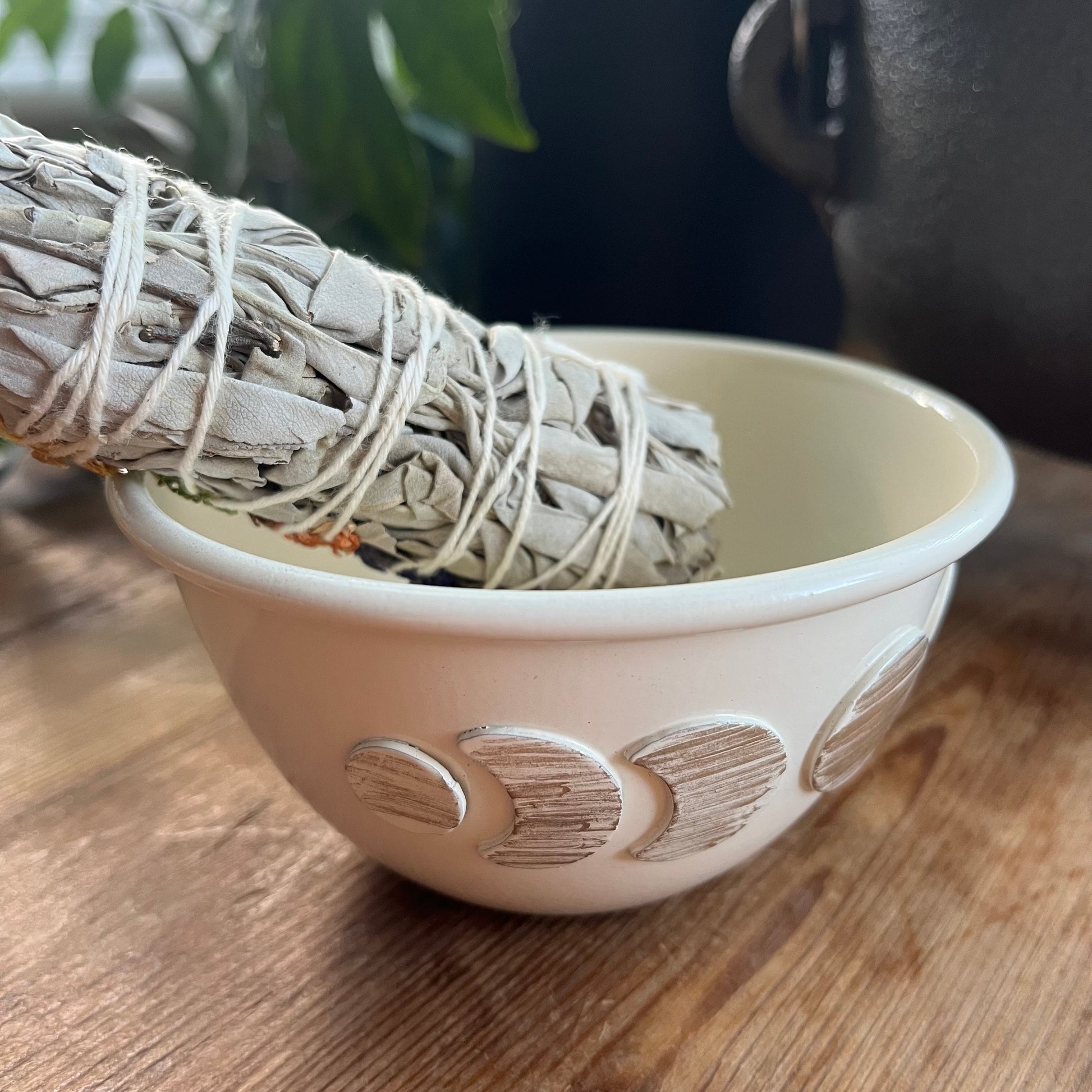White moon phase decorative ceramic smudge bowl on a wooden surface