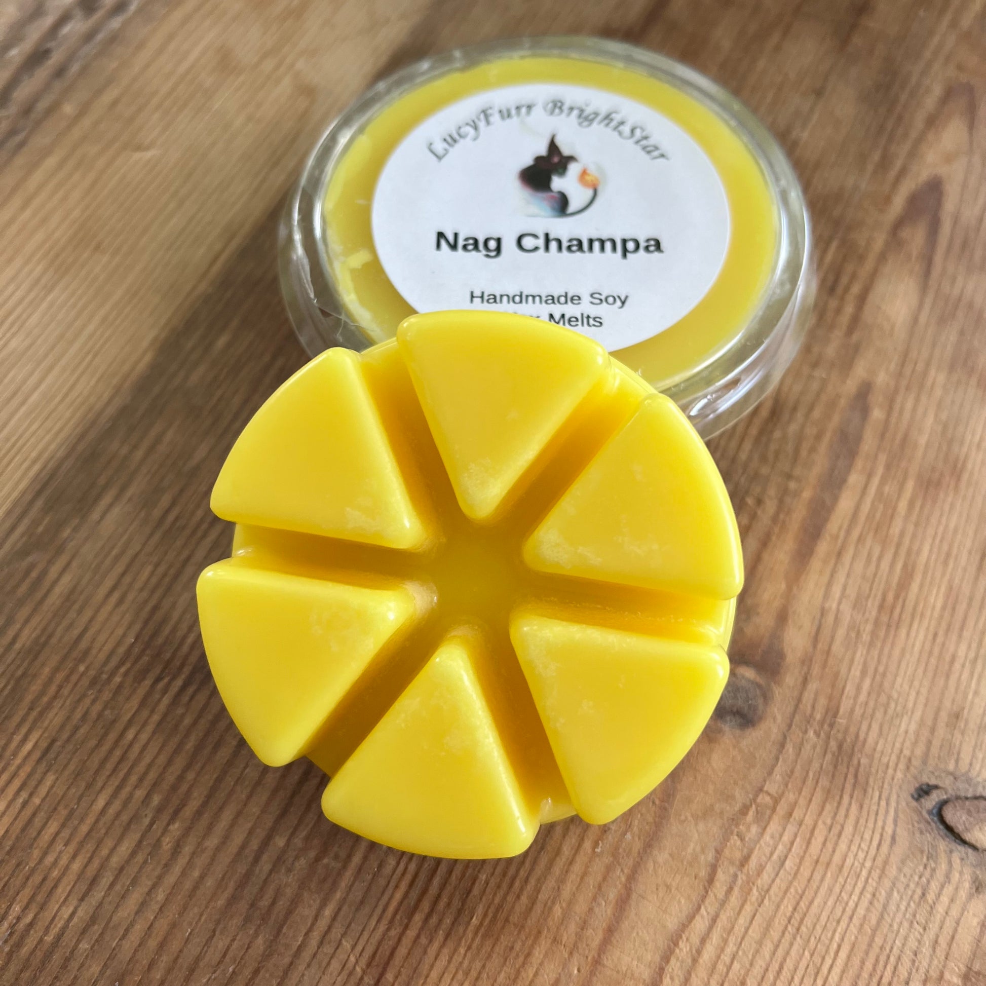 Yellow wax melt with a container labeled 'Nag Champa' on a wooden surface