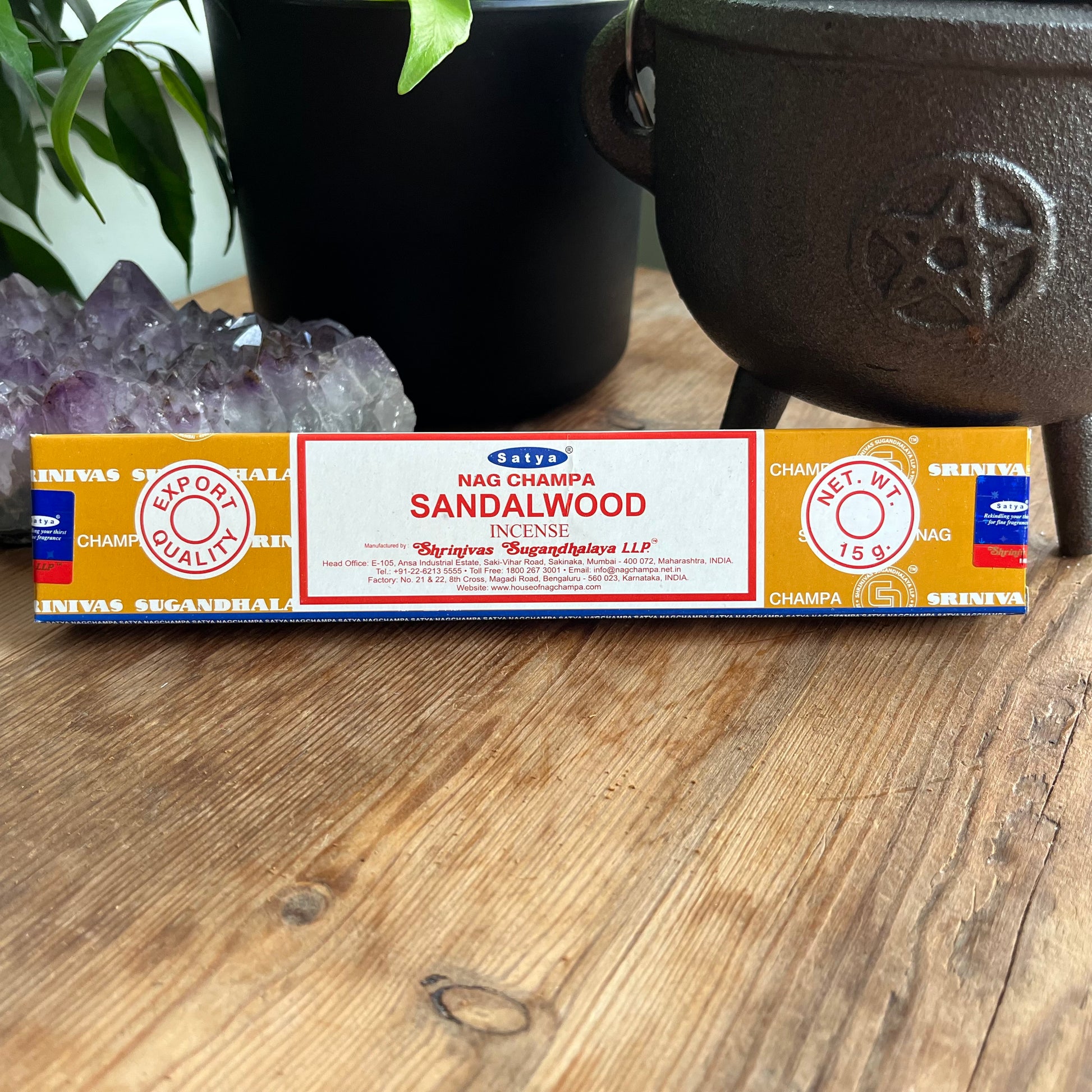 A box of Satya Nag Champa Sandalwood incense, with branding and product information displayed on the packaging, placed on a wooden surface.
