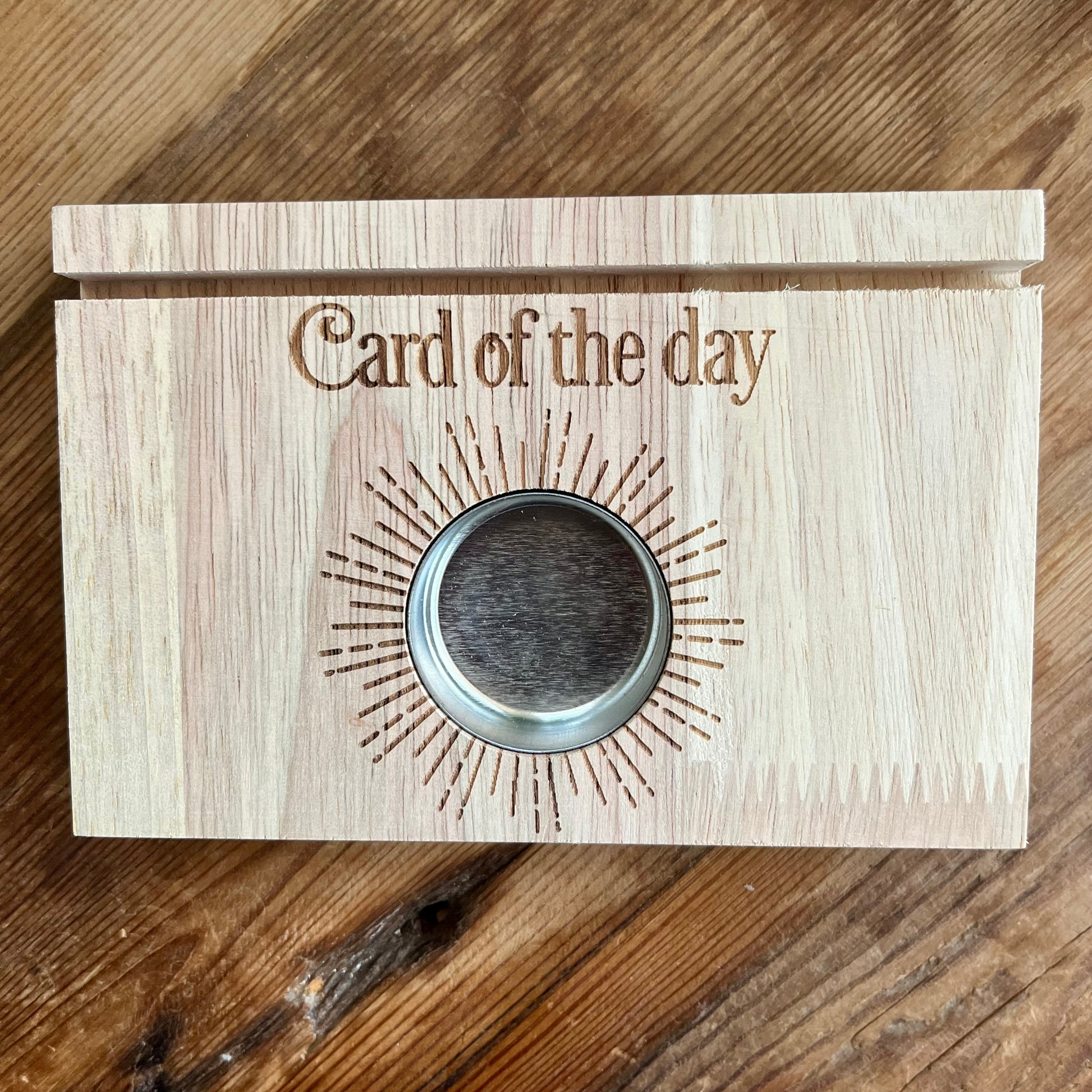 Natural wood Tarot card stand. with words Card of the day etched in the wood.A slot to place Tarot card and hold it upright. Space  will hold 2 cards. A circular cut out filled with a metal tealight holder. 