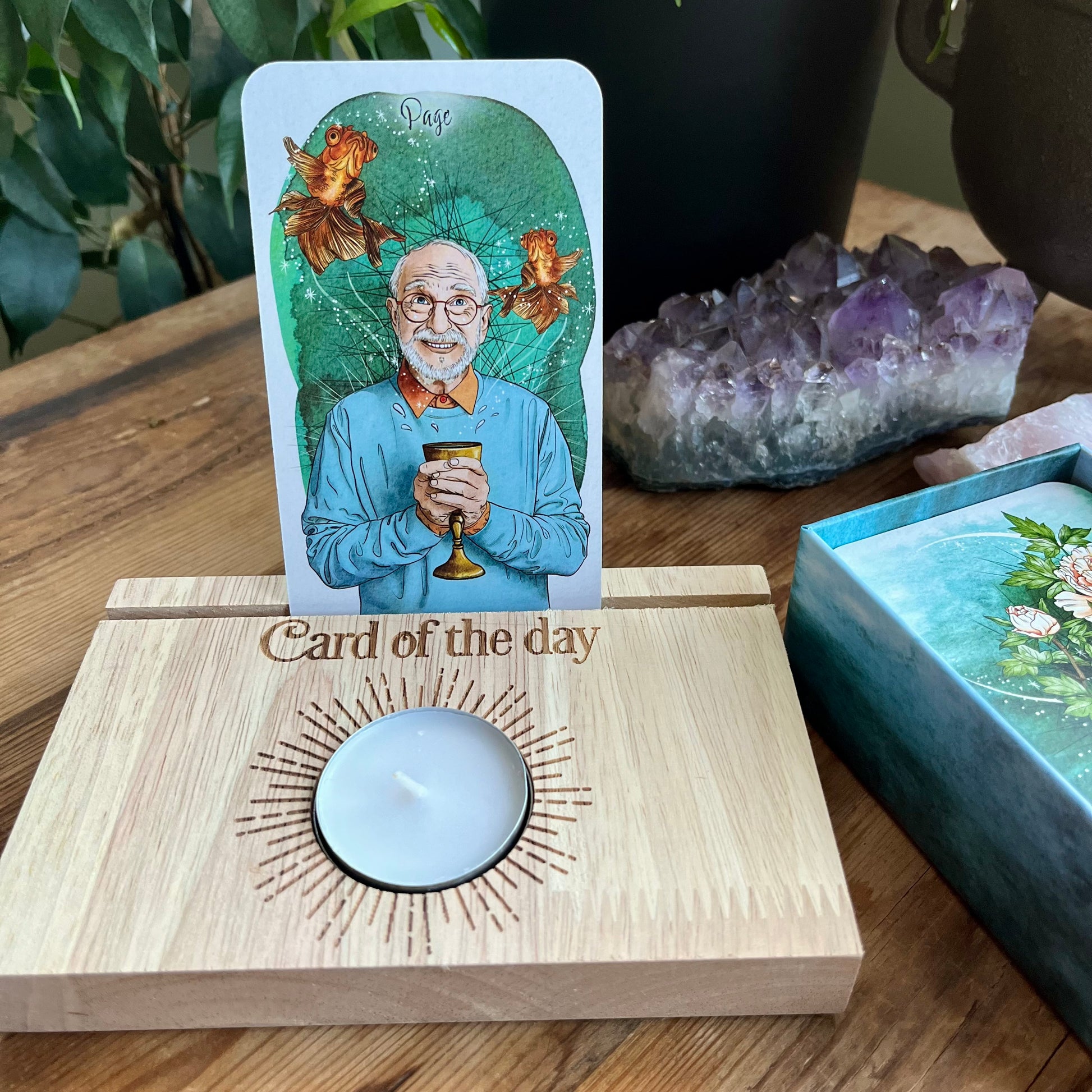 Natural wood Tarot card stand. with words Card of the day etched in the wood.A slot to place Tarot card and hold it upright. Space  will hold 2 cards. A white tealight candle sits within a circular cut out space 