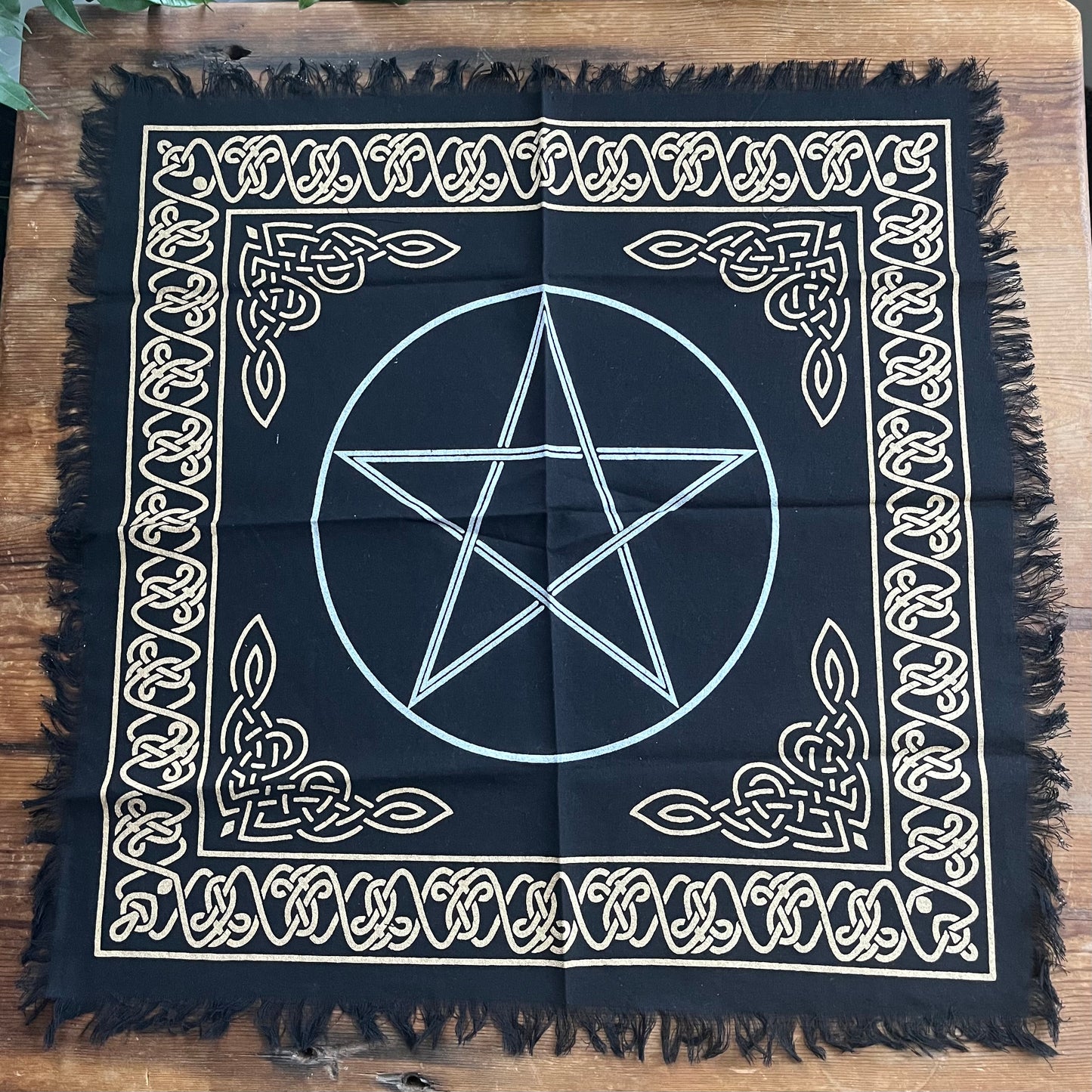 Black square cloth with white pentagram design on a wooden surface