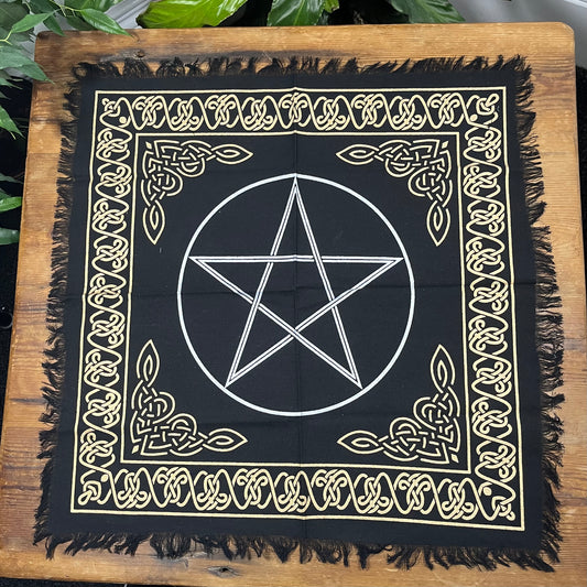 Black cloth with white pentagram design on a wooden surface