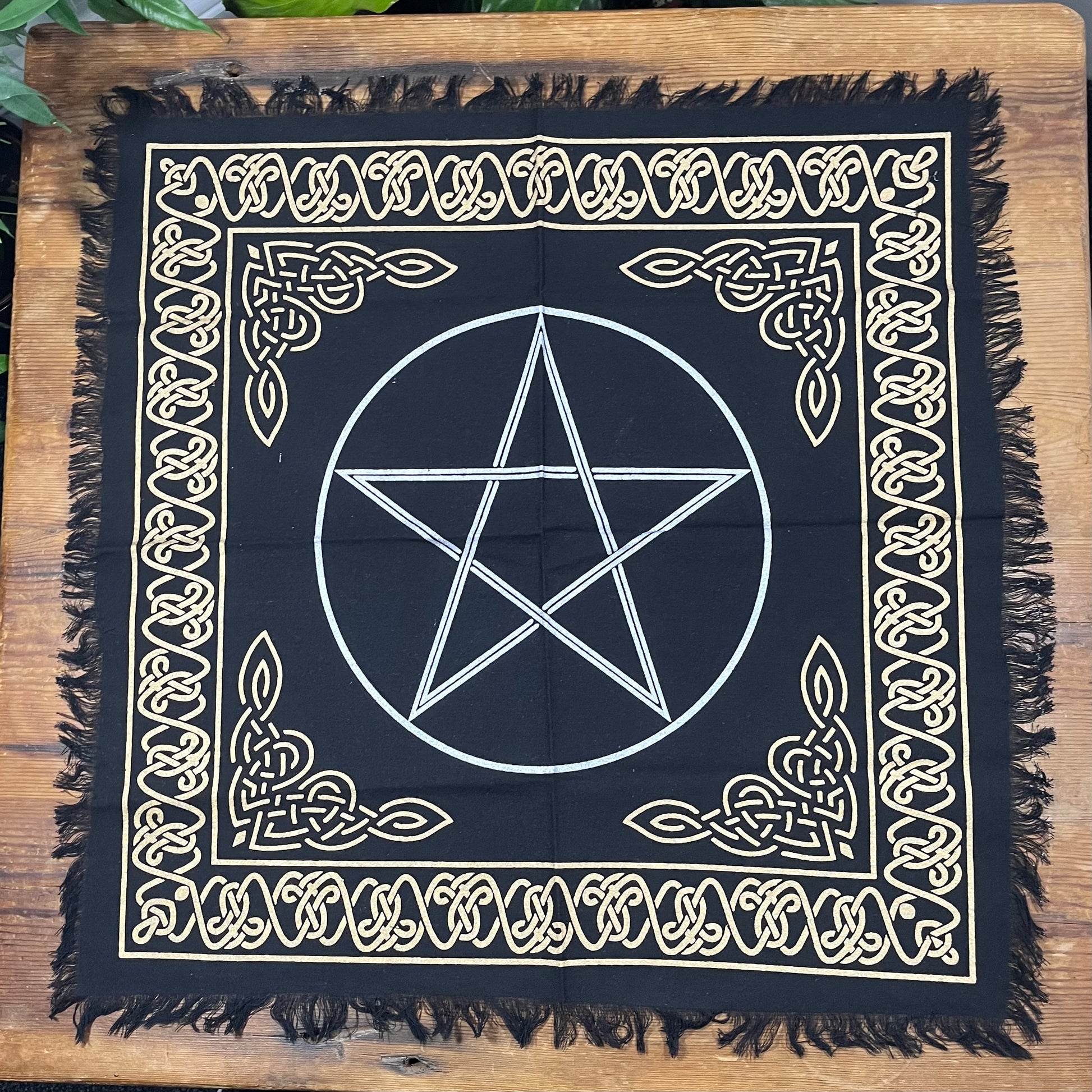 Black square cloth with white pentagram design on a wooden surface