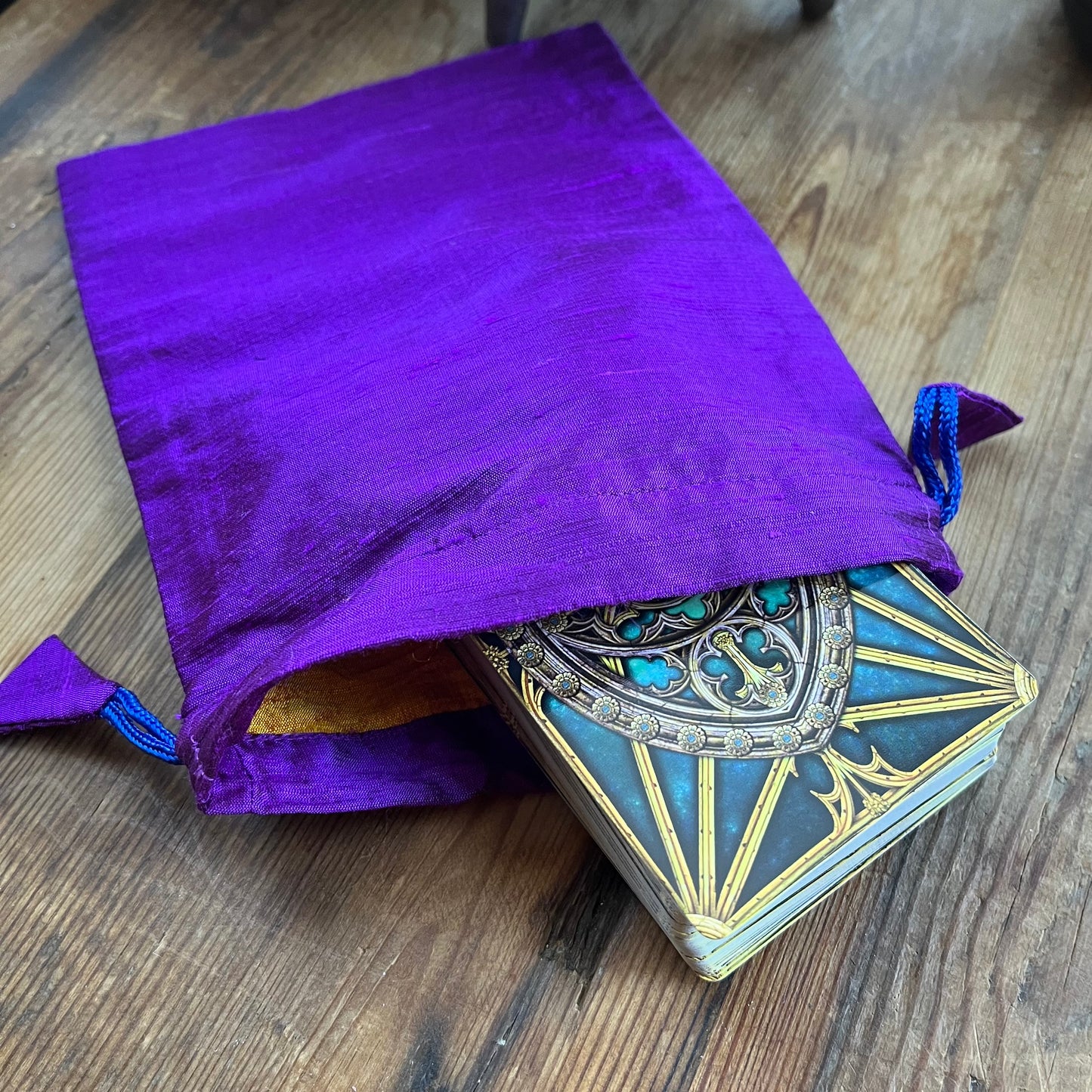 Purple drawstring bag with a deck of cards on a wooden surface