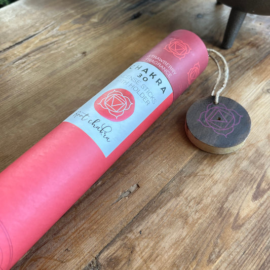 Red cardboard tube holding strawberry scented incense for the Root Chakra with a wooden incense holder with the symbol for the root chakra printed onto it. 