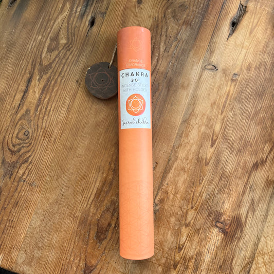 Orange cardboard tube containing 30 sticks of orange scented incense for the Sacral Chakra with a wooden incense holder printed with the Sacral Chakra symbol 