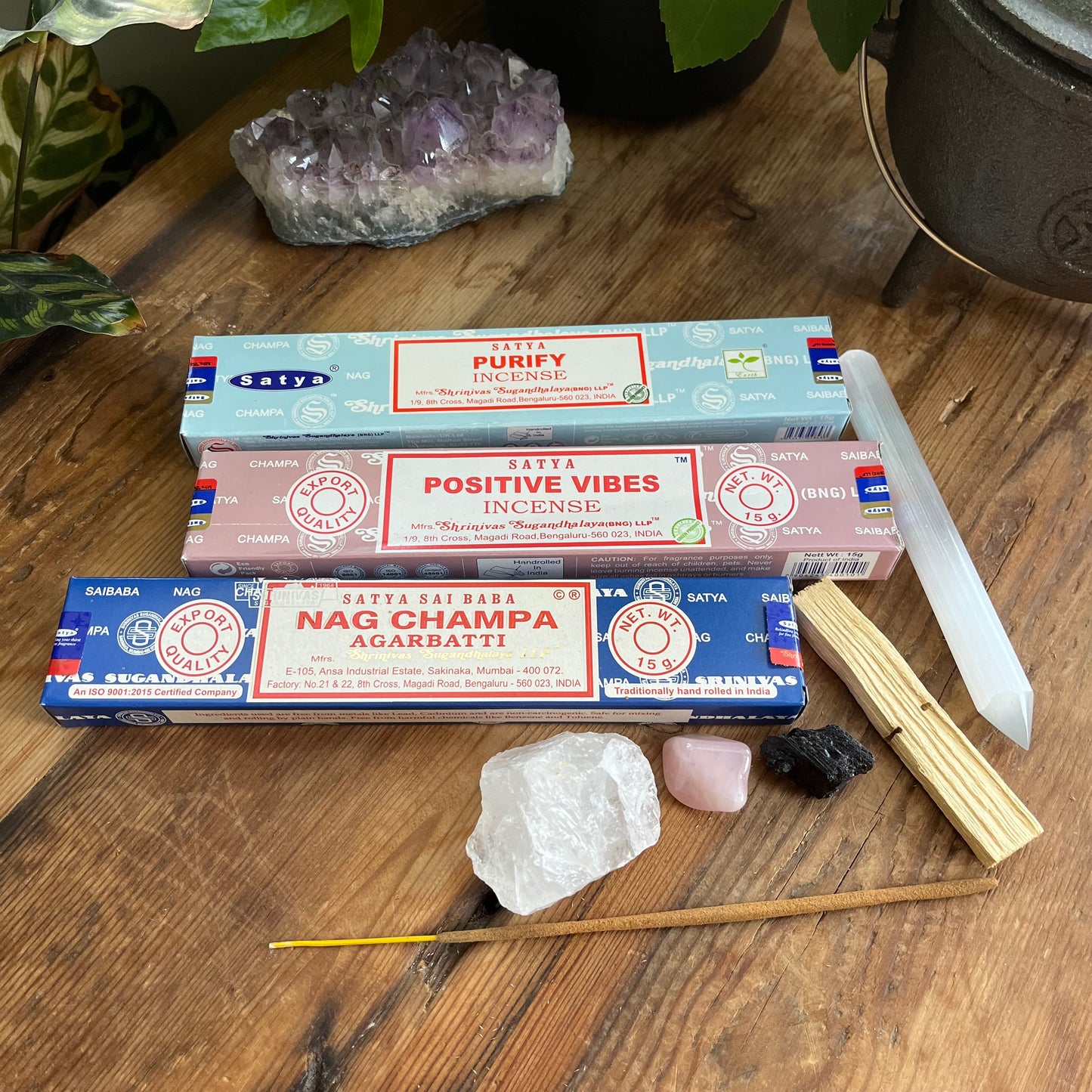 Three Satya incense stick boxes on a wooden surface with crystals and sticks.