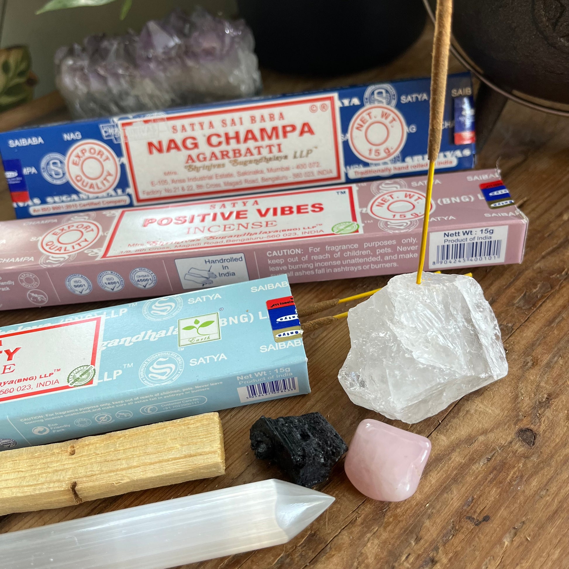 Incense sticks with packaging, crystals, and a crystal wand on a wooden surface