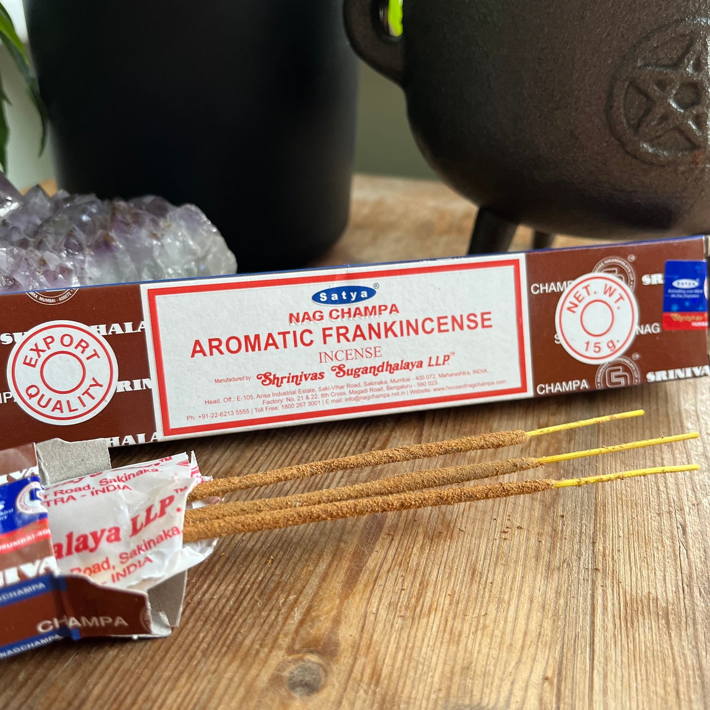 A package of Satya Nag Champa Aromatic Frankincense incense is displayed on a wooden surface.