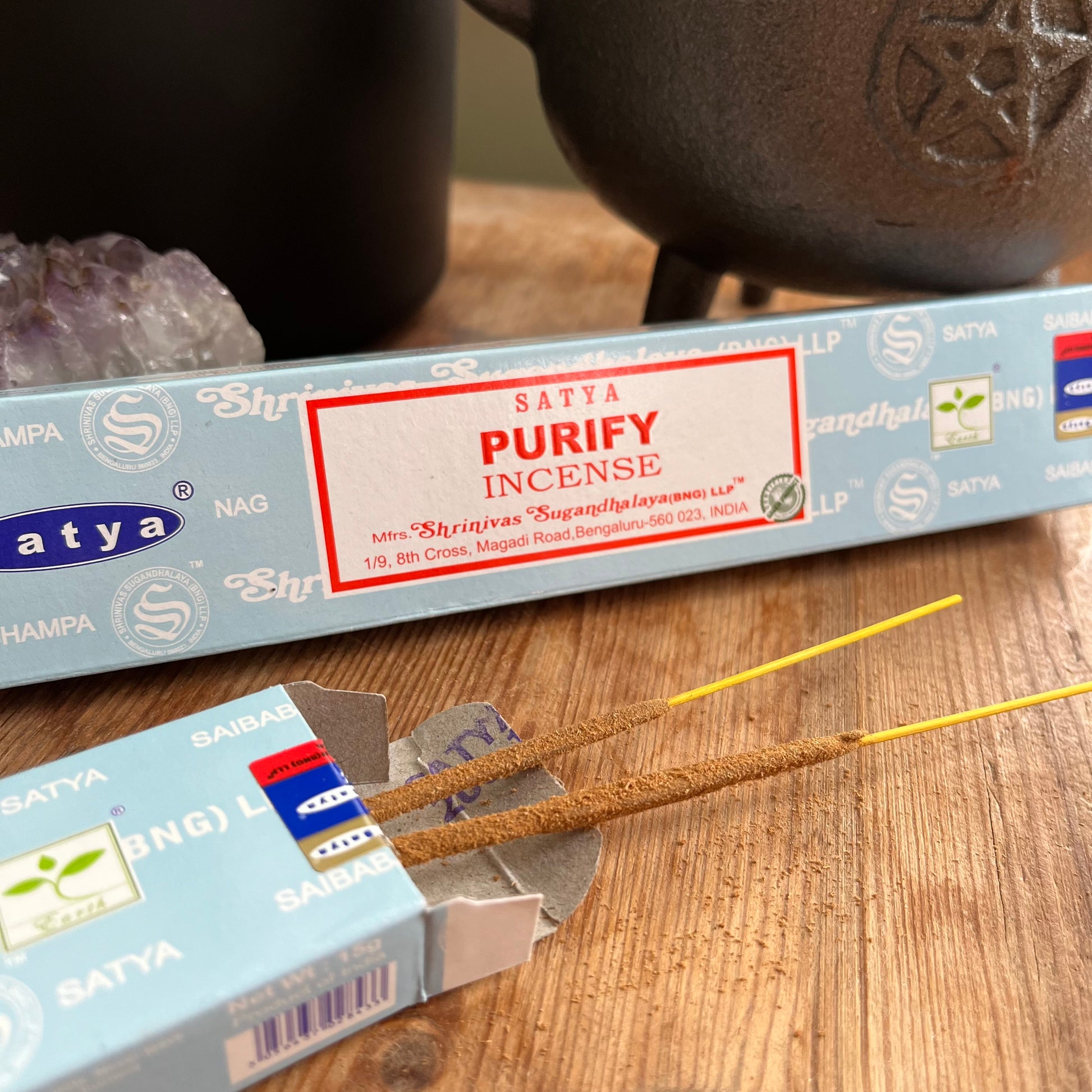 A box of Satya Purify incense placed on a wooden surface, with the brand name and product description visible.