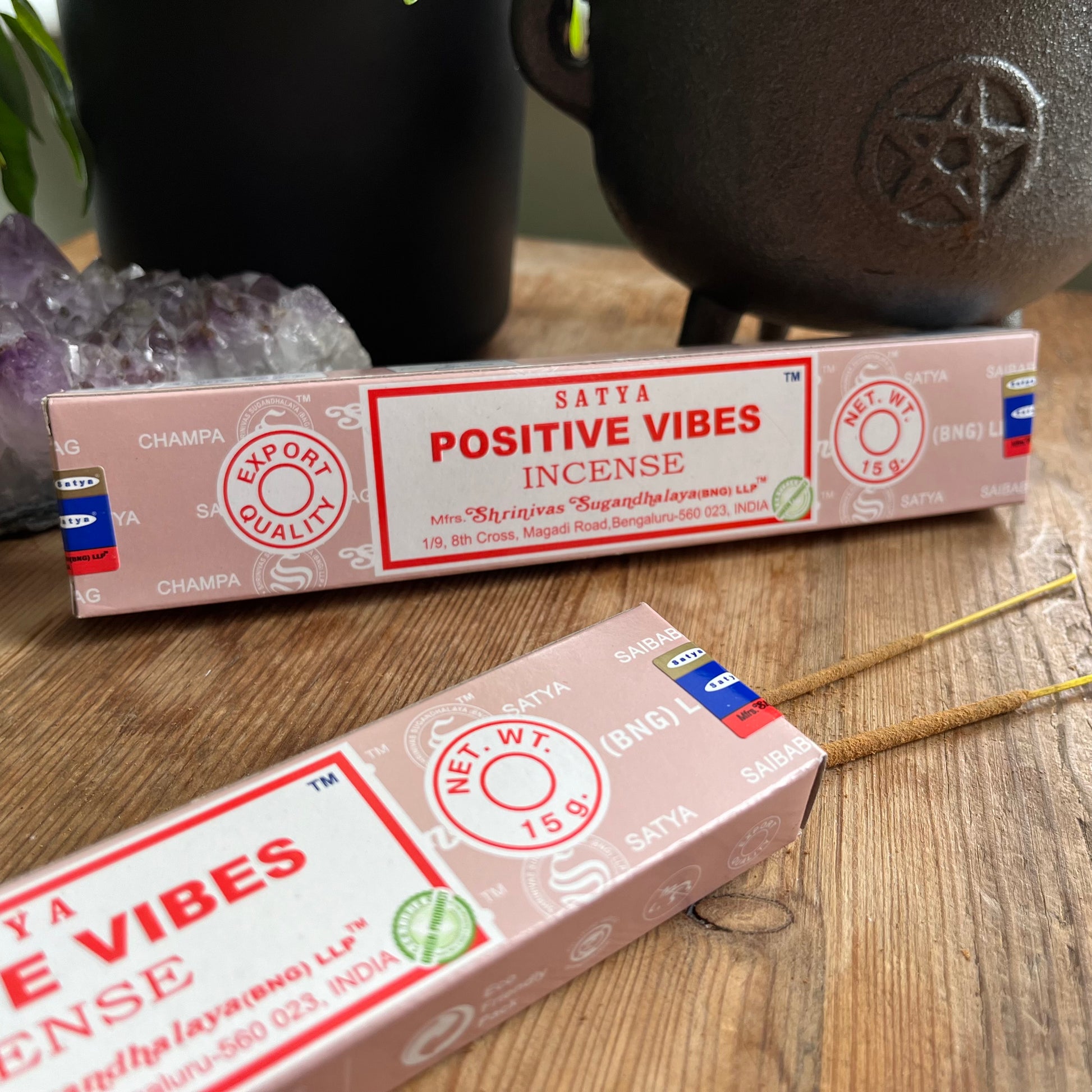 Two boxes of satya positive vibes incense on a wooden table, one box is open and some incense sticks are peeping out 