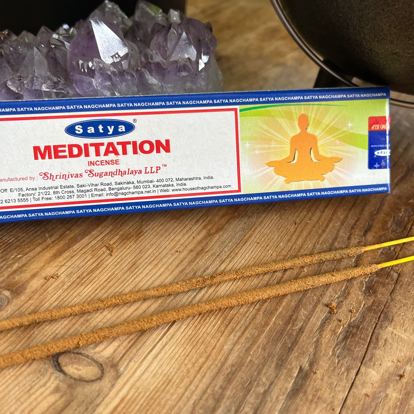 box of satya meditation incense with some loose incens sticks on a wooden table