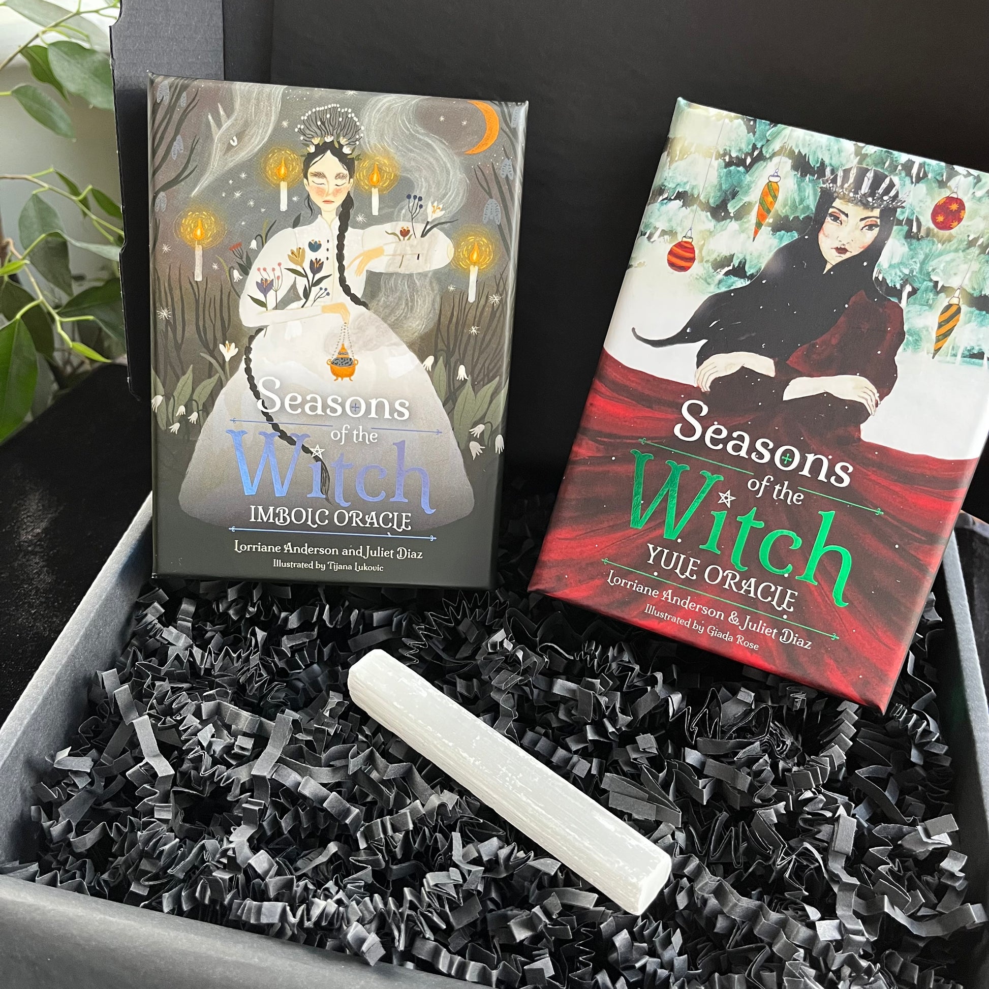 Two 'Seasons of the Witch' oracle card boxes with a white candle on black crinkled paper