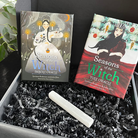 Two 'Seasons of the Witch' oracle card boxes with a white candle on black crinkled paper