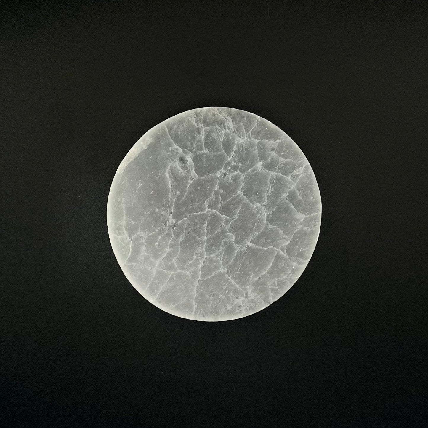 A circular Selenite cystal charging plate centered against a solid black background.