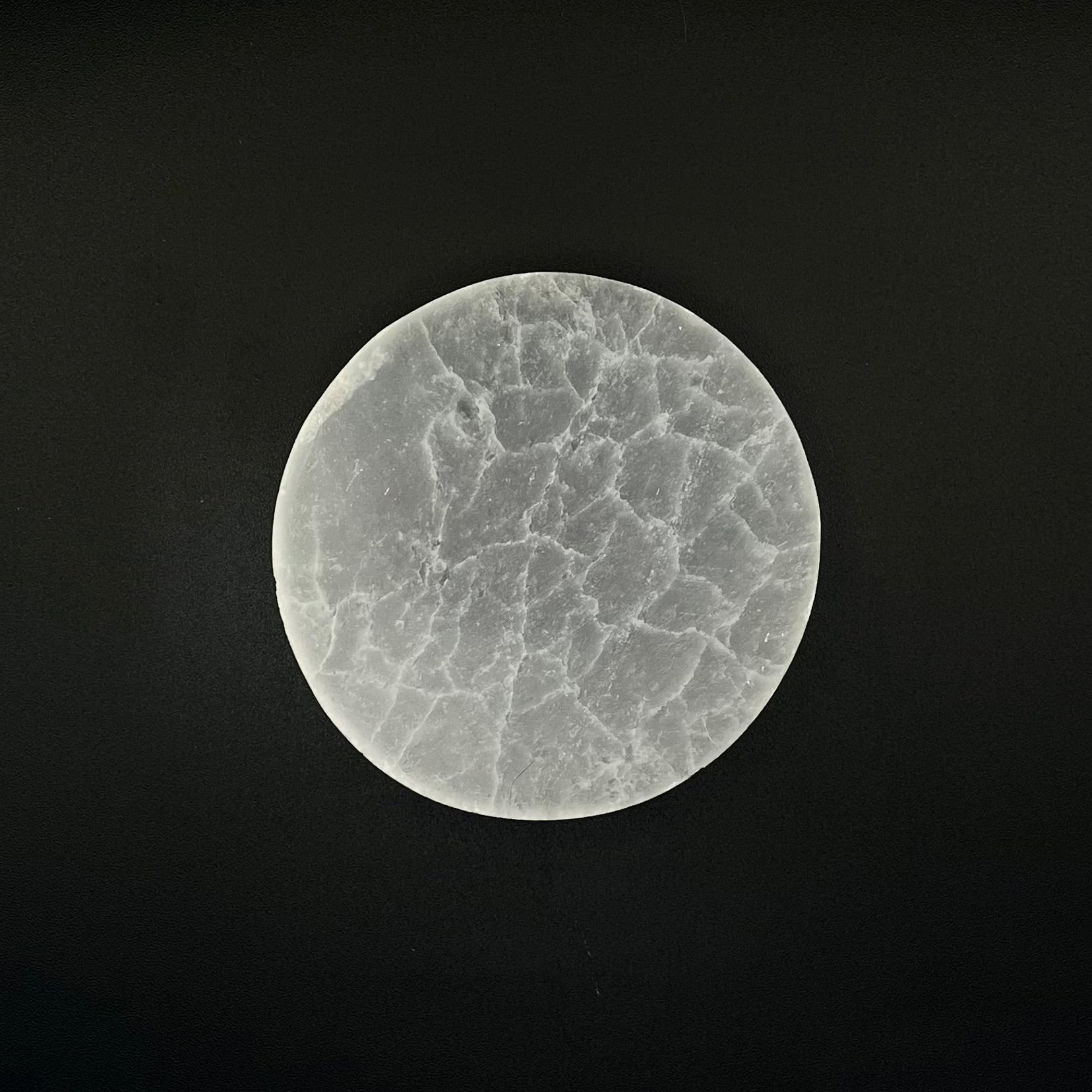 A circular Selenite cystal charging plate centered against a solid black background.