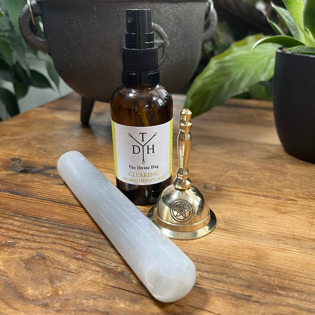 Bottle of 'The Divine Hog' product on a wooden surface with a crystal and bell.