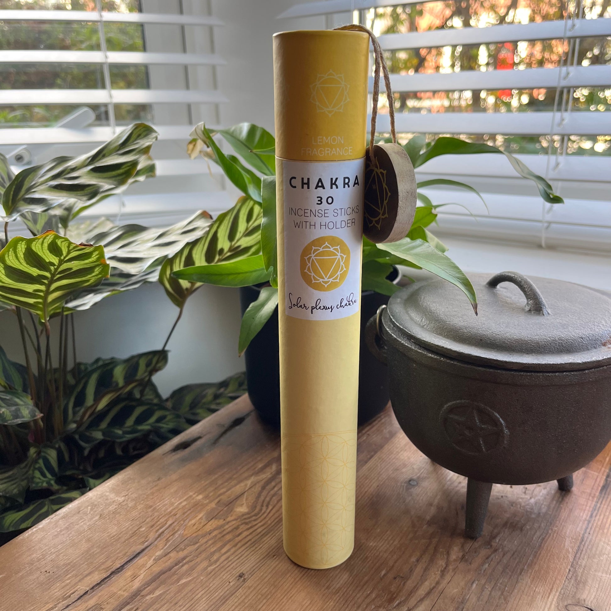Yellow cardboard tube contining 30 sticks of lemon scented incense for the solar plexus chakra with a wooden incense holder printed withthe symbol for the solar plexus 