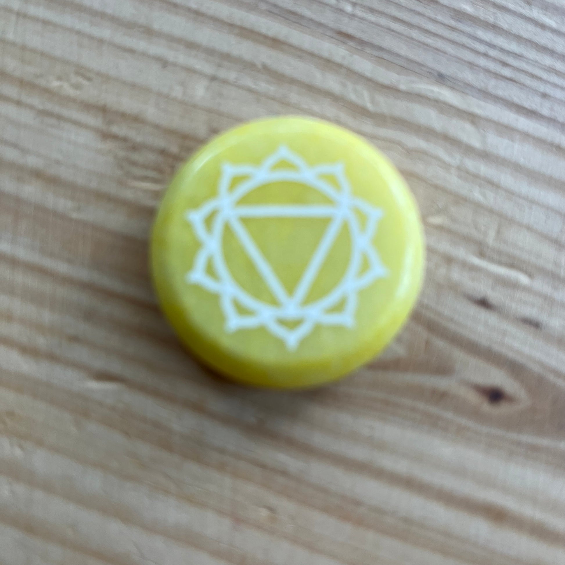 Yellow flat circular meditation stone is engraved with the Solar Plexus Chakra symbol 