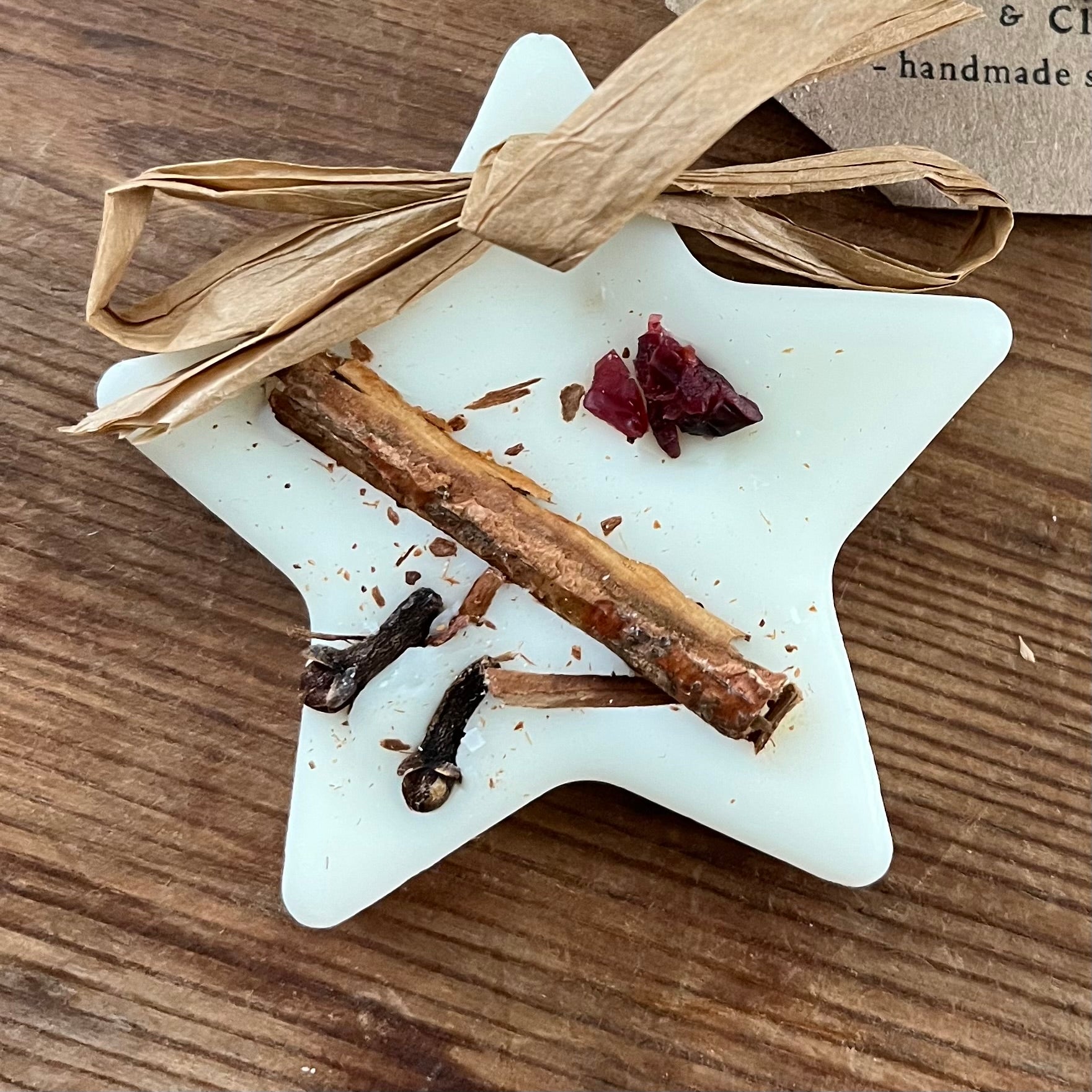 Star-shaped hanging wax melt with cinnamon sticks and dried berries on a wooden surface