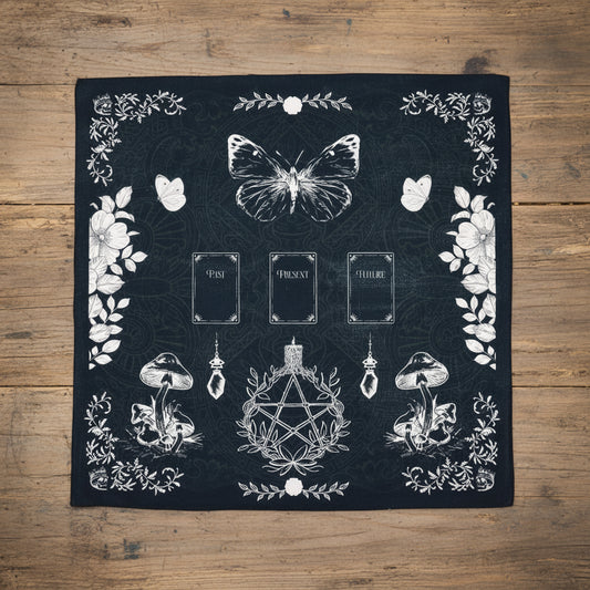 Black Tarot reading cloth with white illustrations of a butterfly, mushrooms, and a pentacle design.