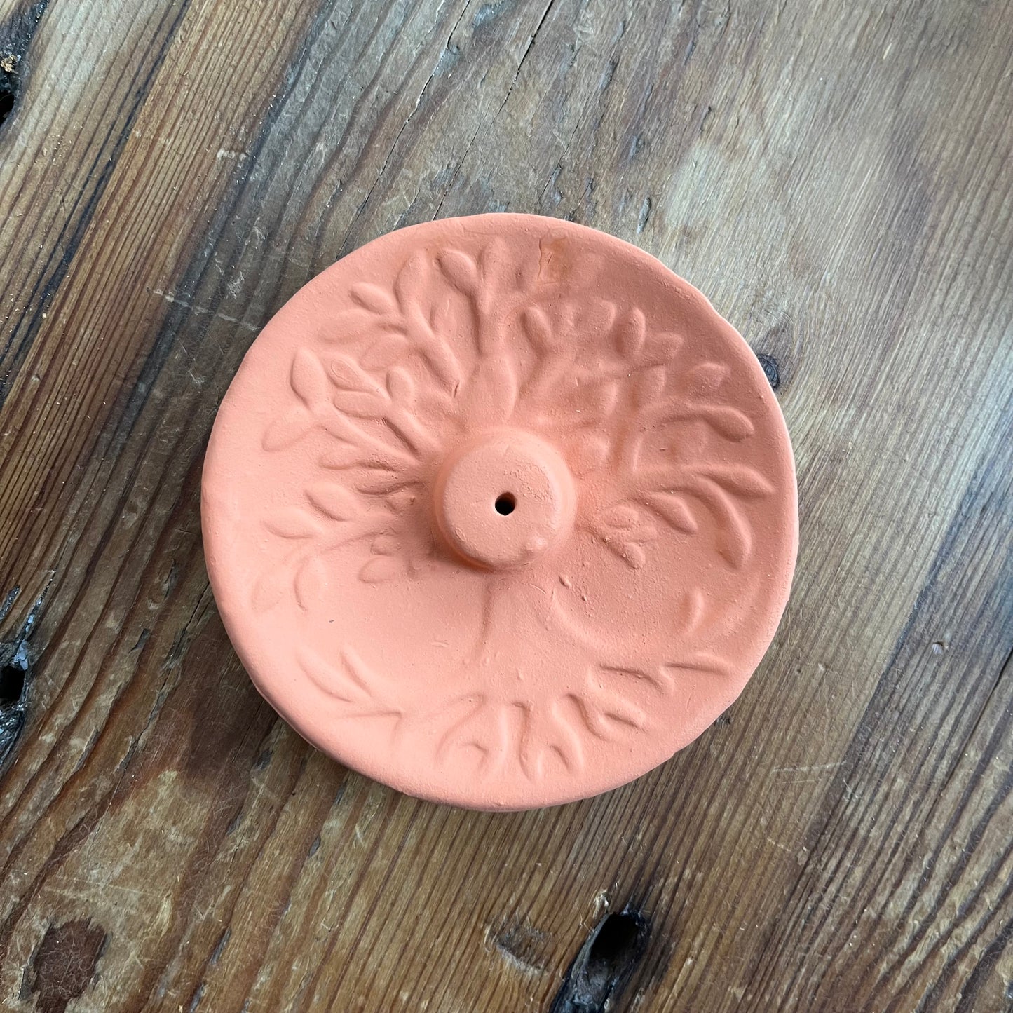 Terracotta Incense Plate with a Tree of Life design n the surface and the hole for the incense stick in the centre 