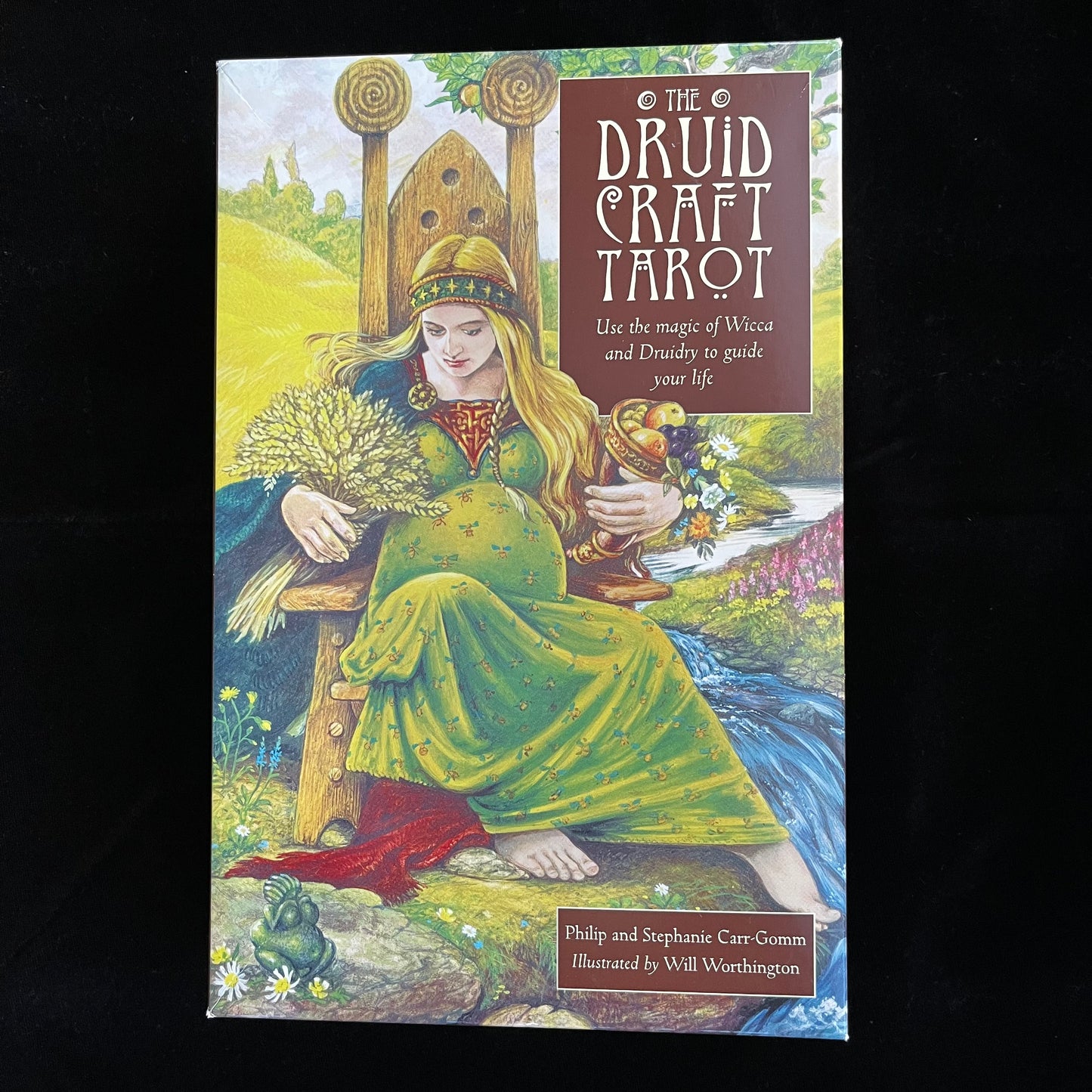 Box cover of 'The Druid Craft Tarot' with an illustration of a woman in a green dress sitting outdoors.