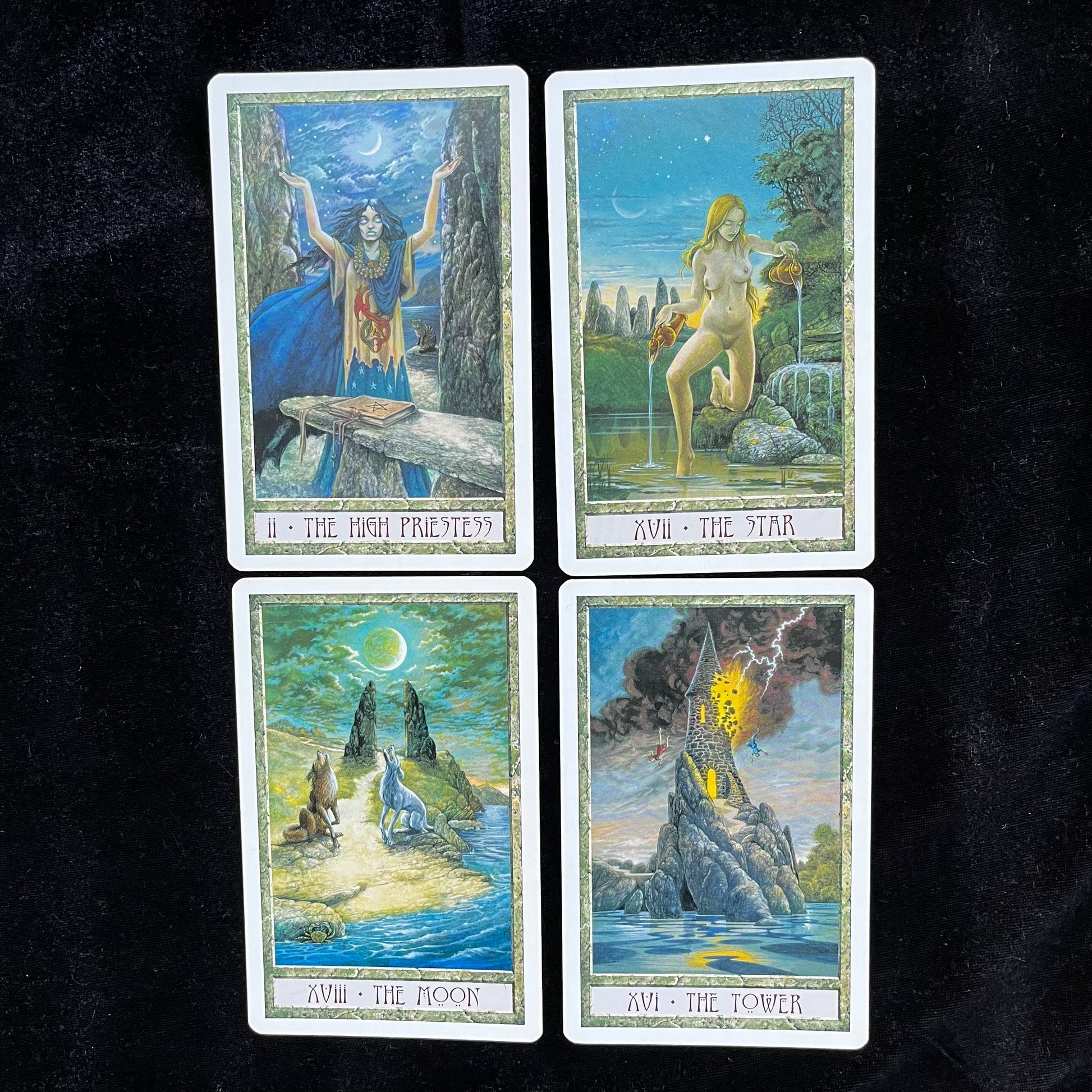 Four tarot cards with artistic illustrations on a black background