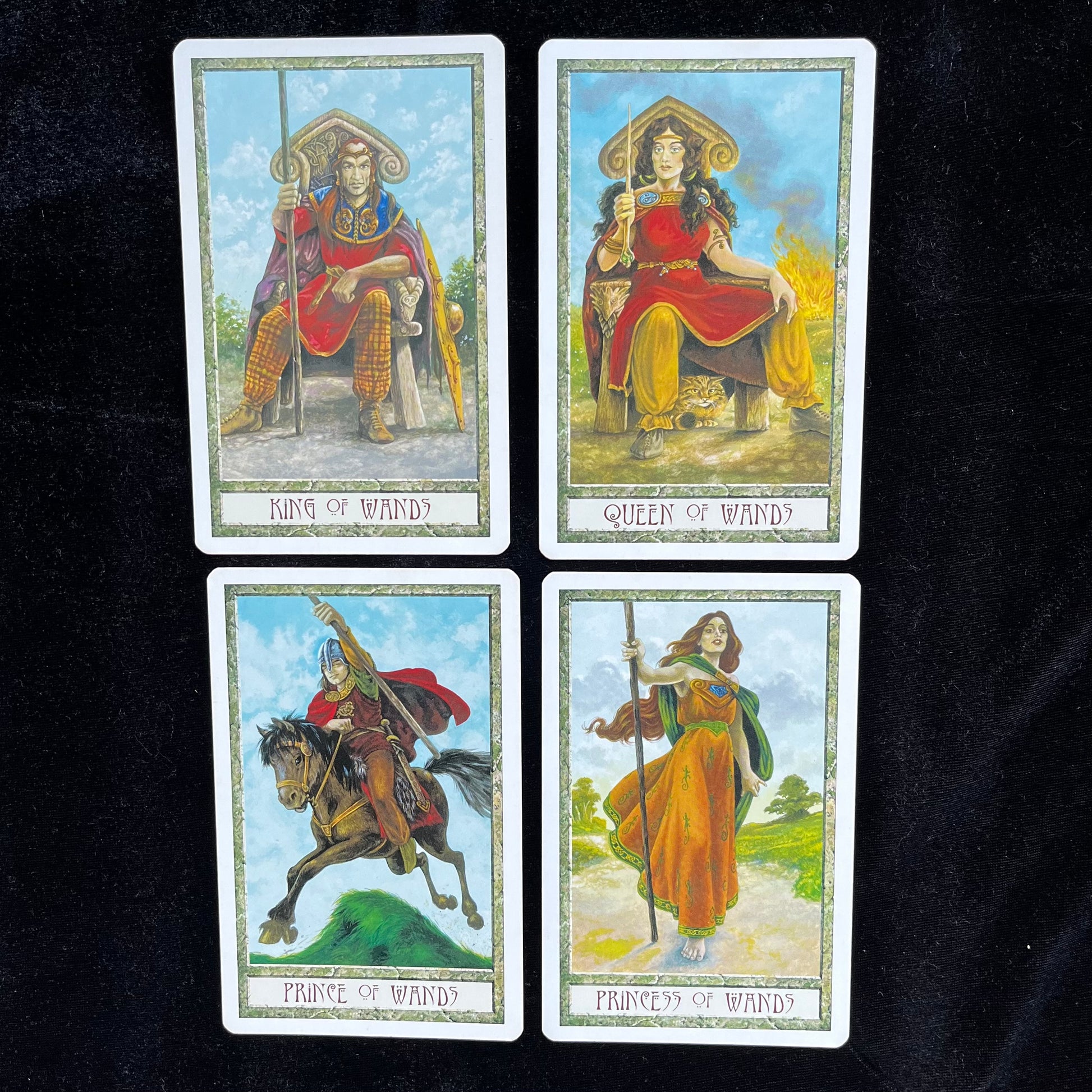 Four tarot cards featuring King, Queen, Prince, and Princess of Wands on a dark background.