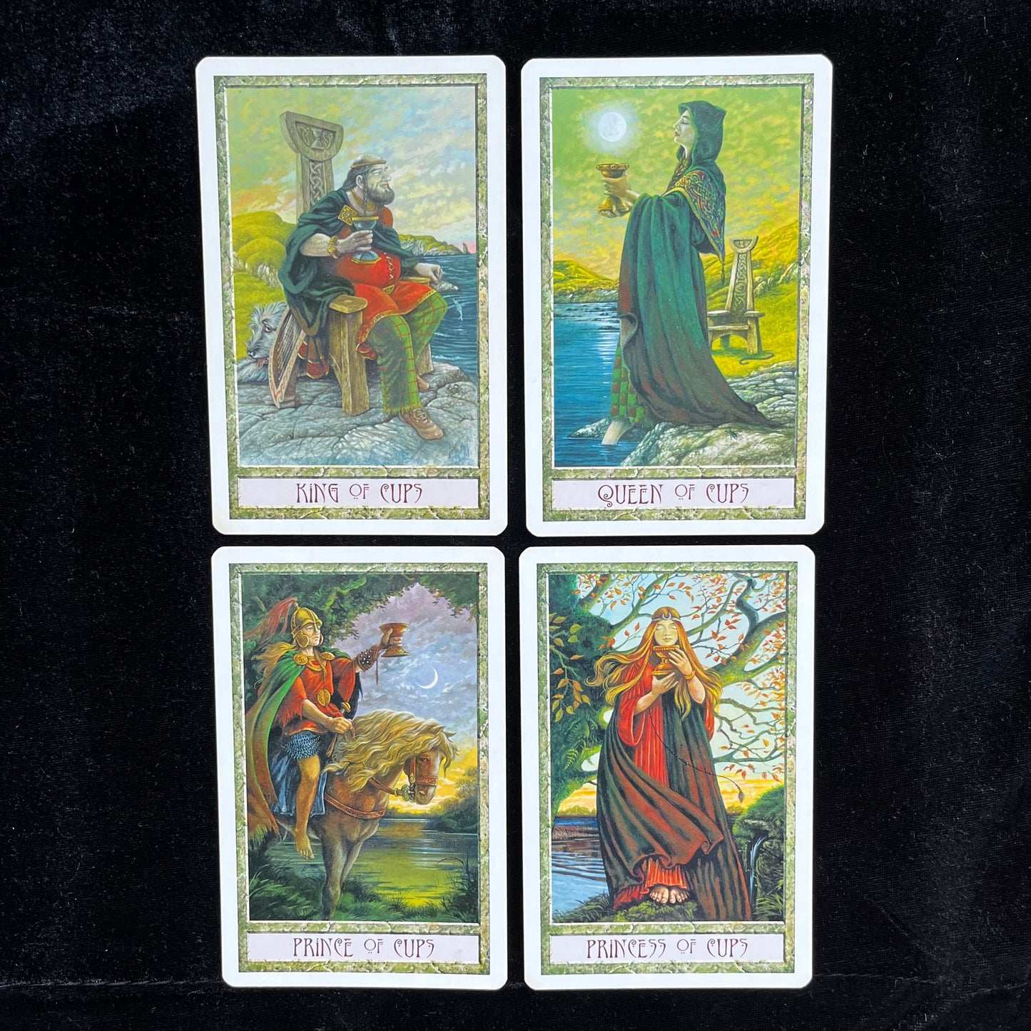 Four tarot cards featuring the King, Queen, Prince, and Princess of Cups on a dark background.