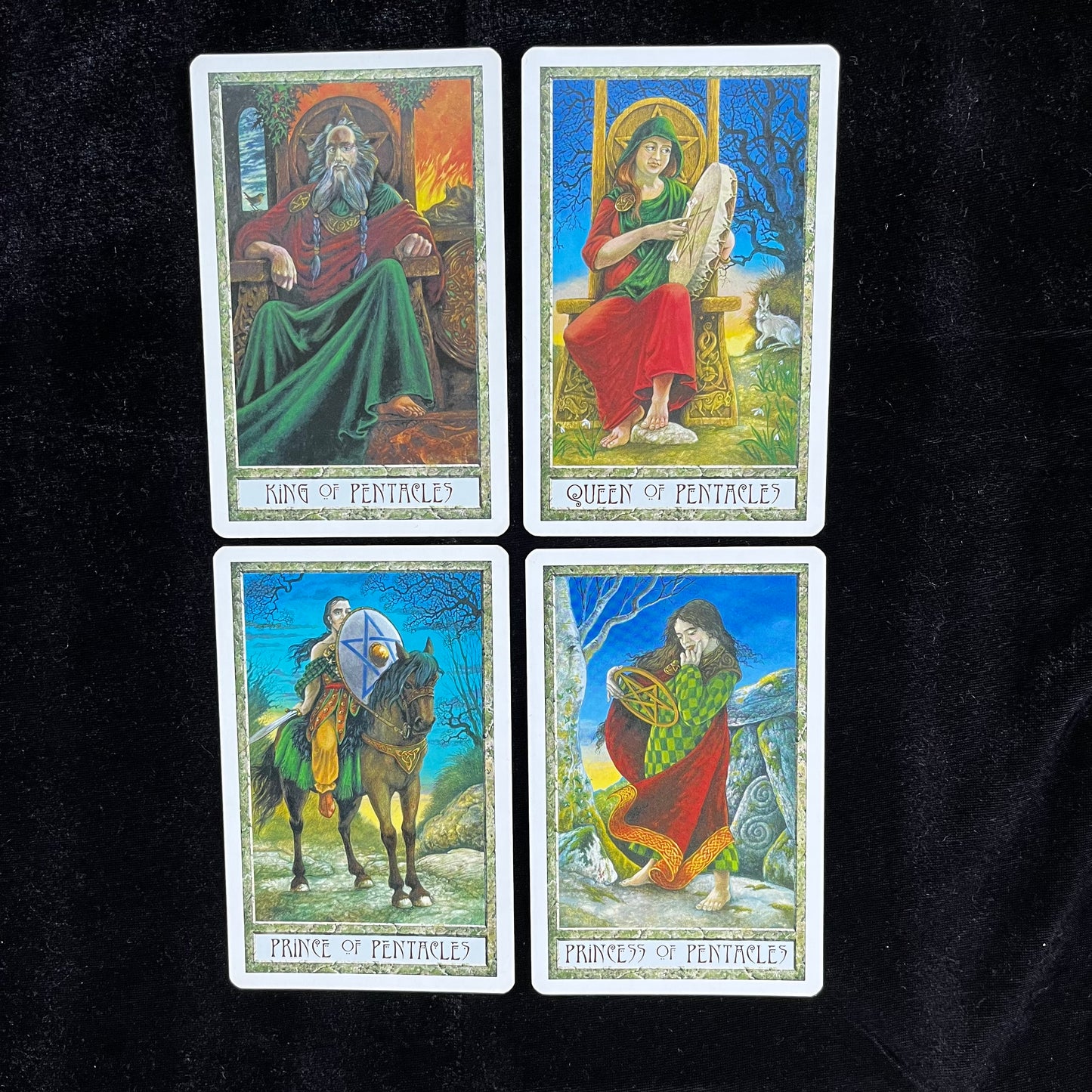 Four tarot cards featuring different figures on a black background