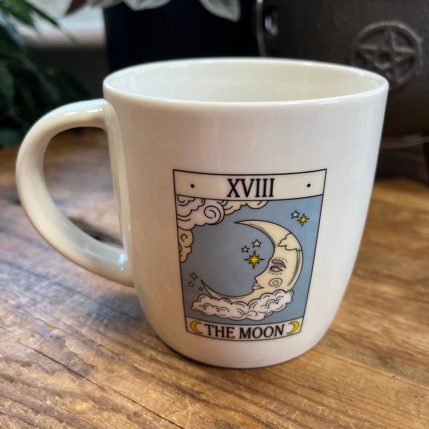 White mug with 'The Moon' tarot card design on a wooden surface