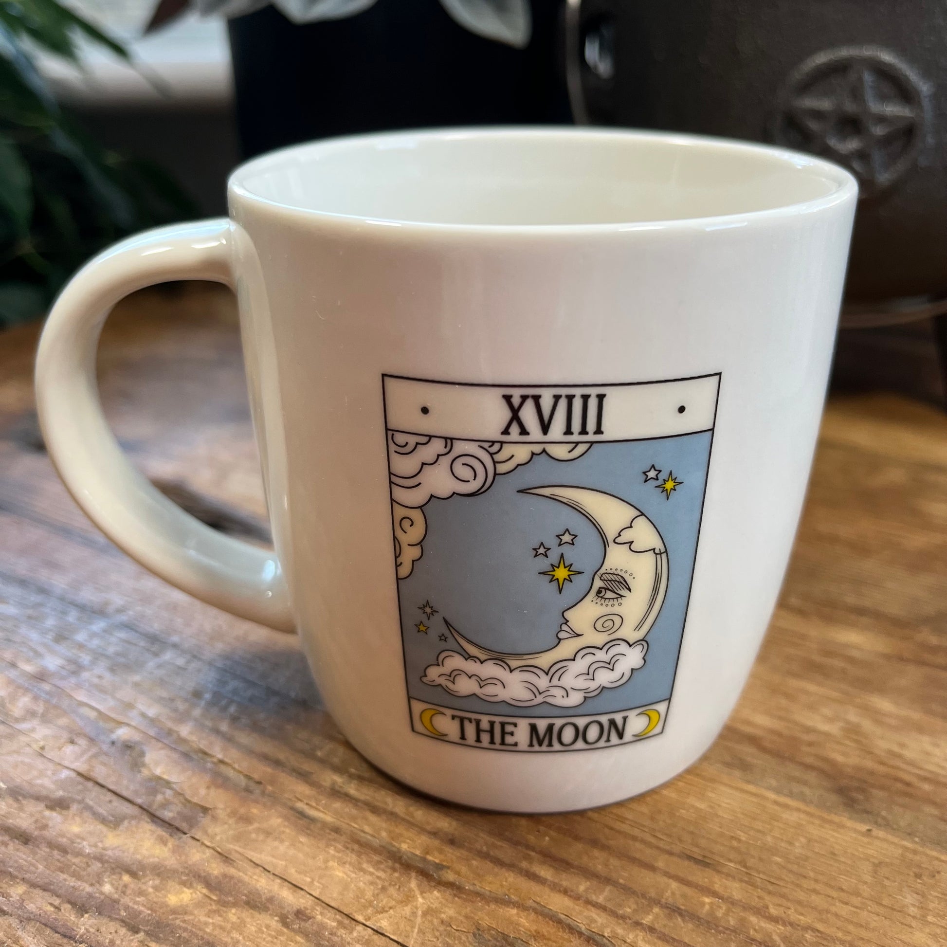White mug with 'The Moon' tarot card design on a wooden surface
