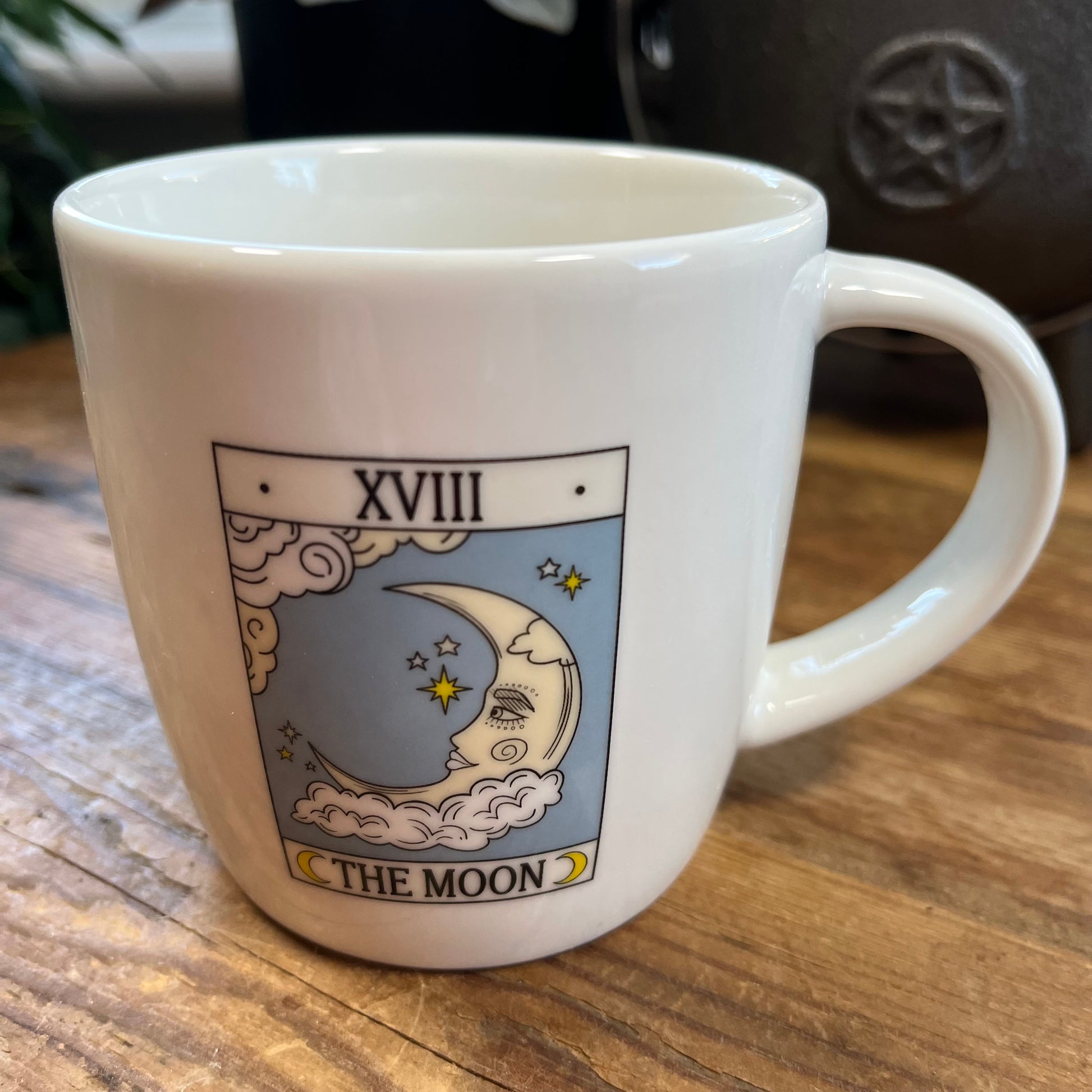 White mug with 'The Moon' tarot card design on a wooden surface