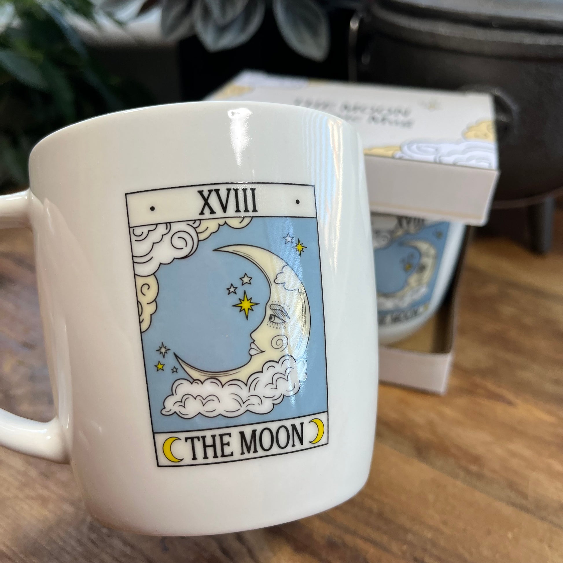 White mug with 'The Moon' tarot card design on a wooden surface