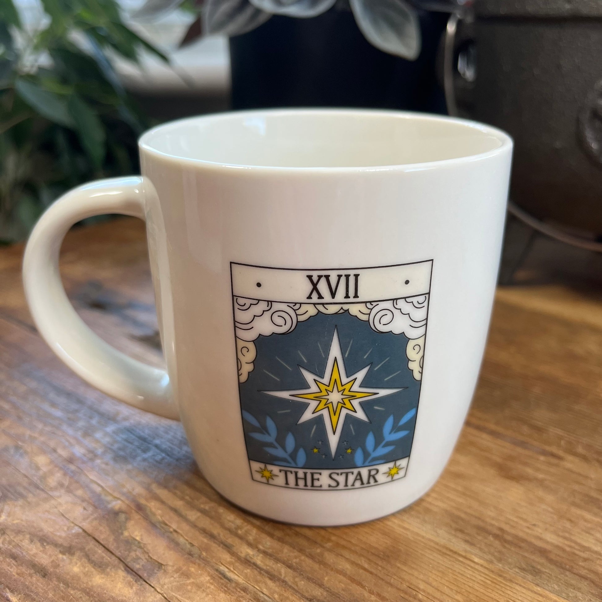 White mug with 'The Star' tarot card design on a wooden surface