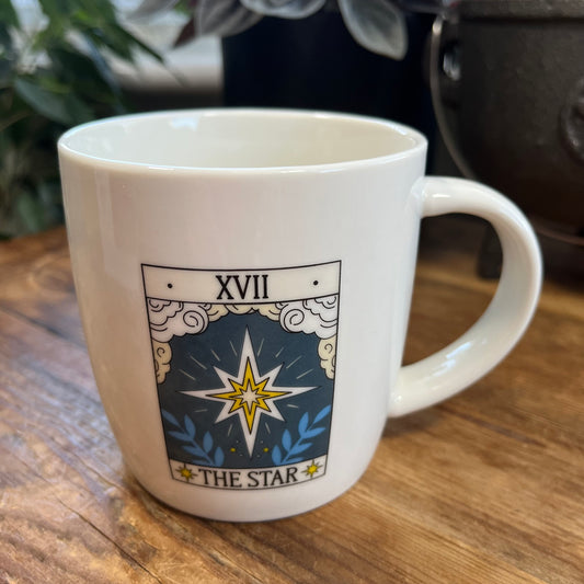 White mug with 'The Star' tarot card design on a wooden surface