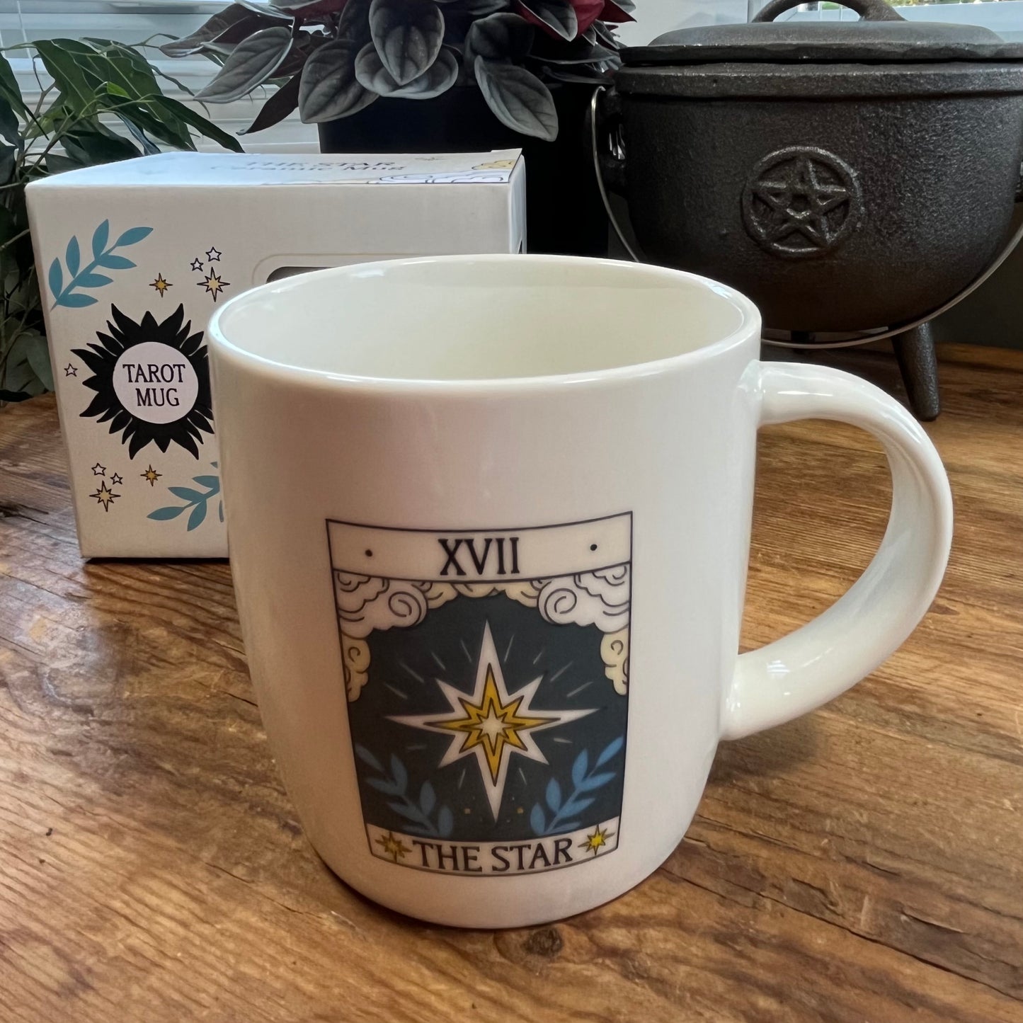 White mug with 'The Star' tarot card design on a wooden surface, next to a box labeled 'Tarot Mug'.