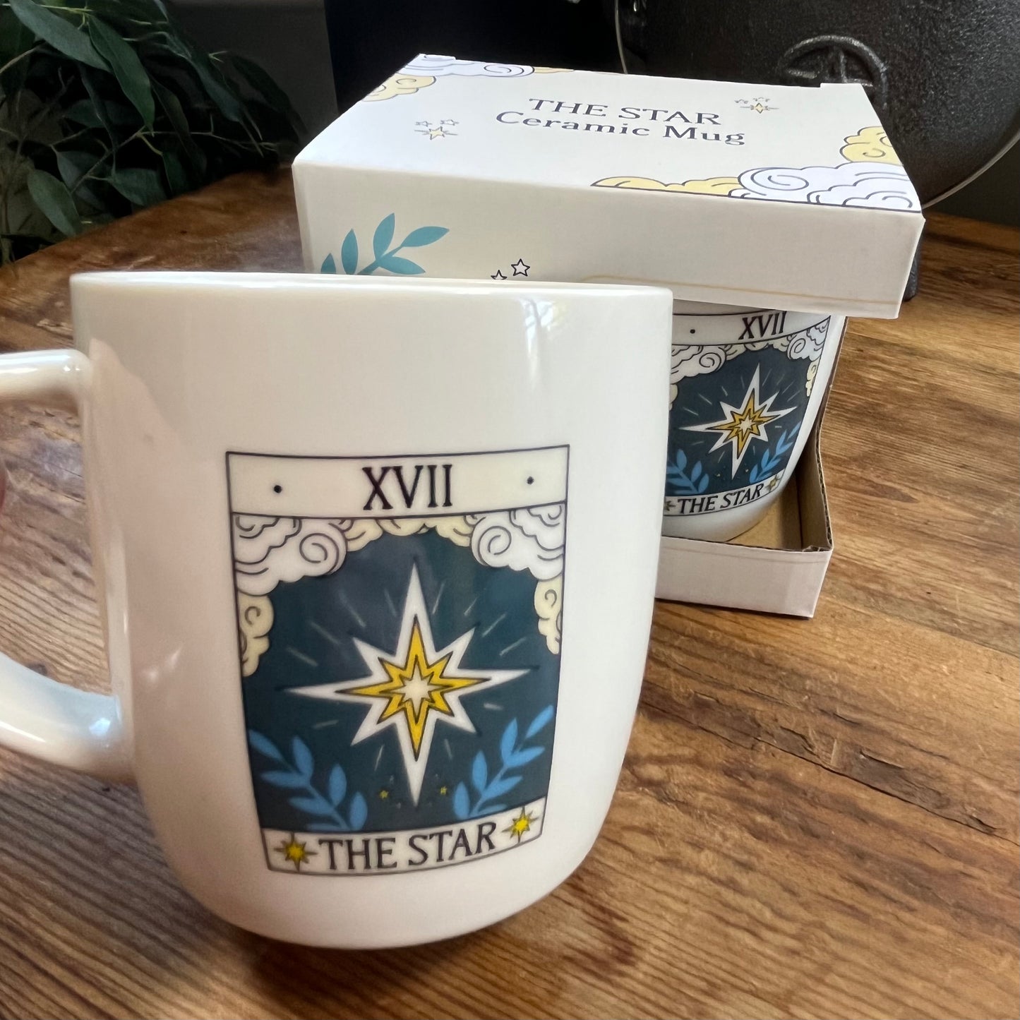 Ceramic mug with 'The Star' tarot design and packaging on a wooden surface