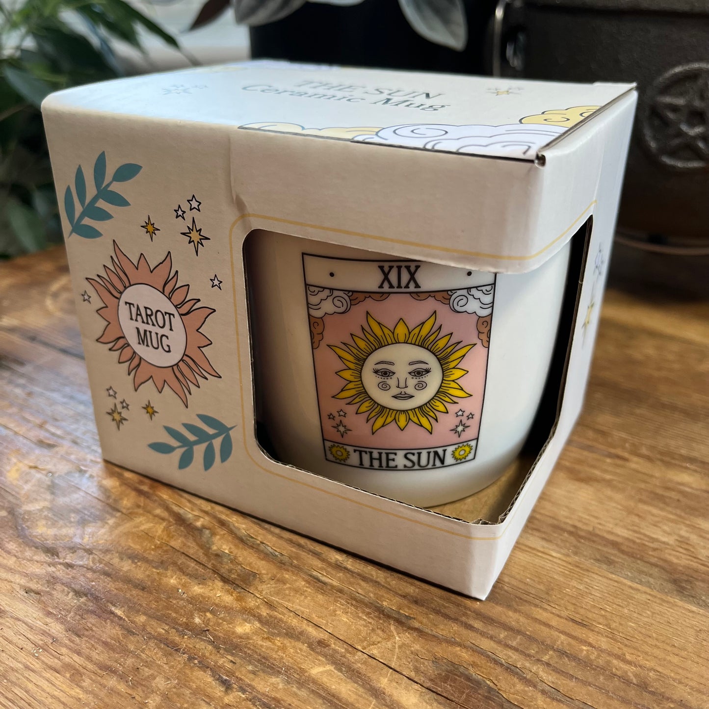 Mug with 'The Sun' design in a box on a wooden surface