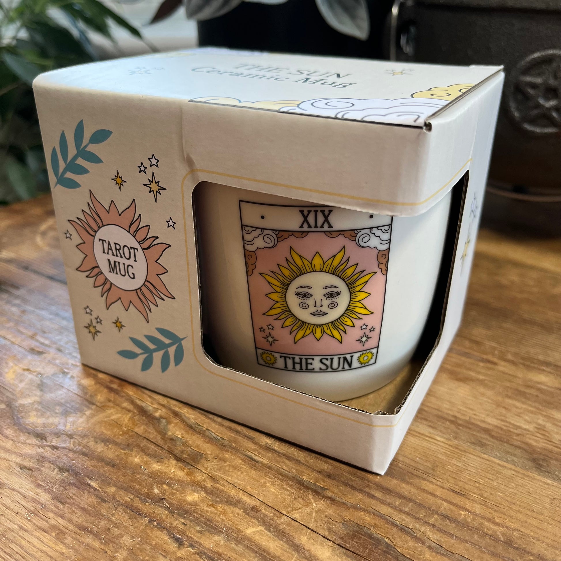 Mug with 'The Sun' design in a box on a wooden surface