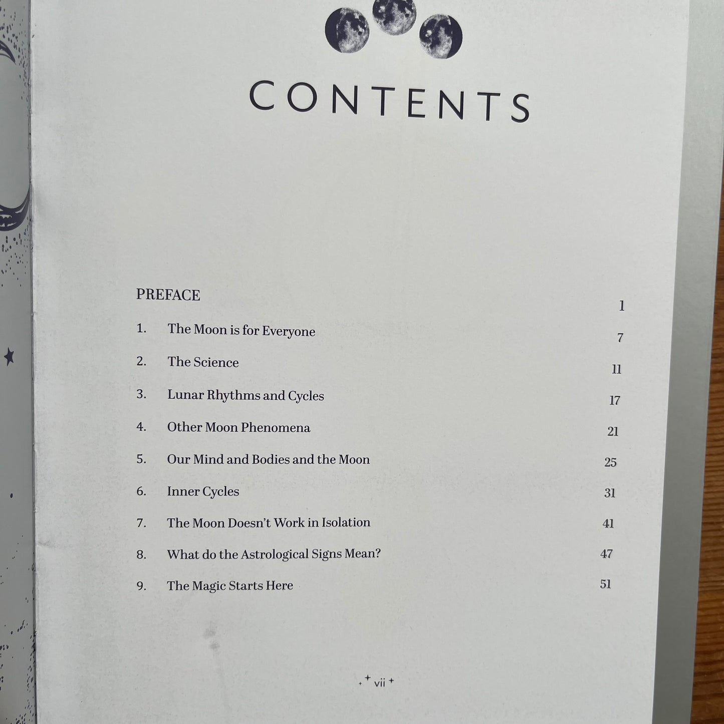A printed book showing the contents list with the title 'CONTENTS' and a table of contents under 'PREFACE' about moon and astrology topics, photographed on a wooden surface.